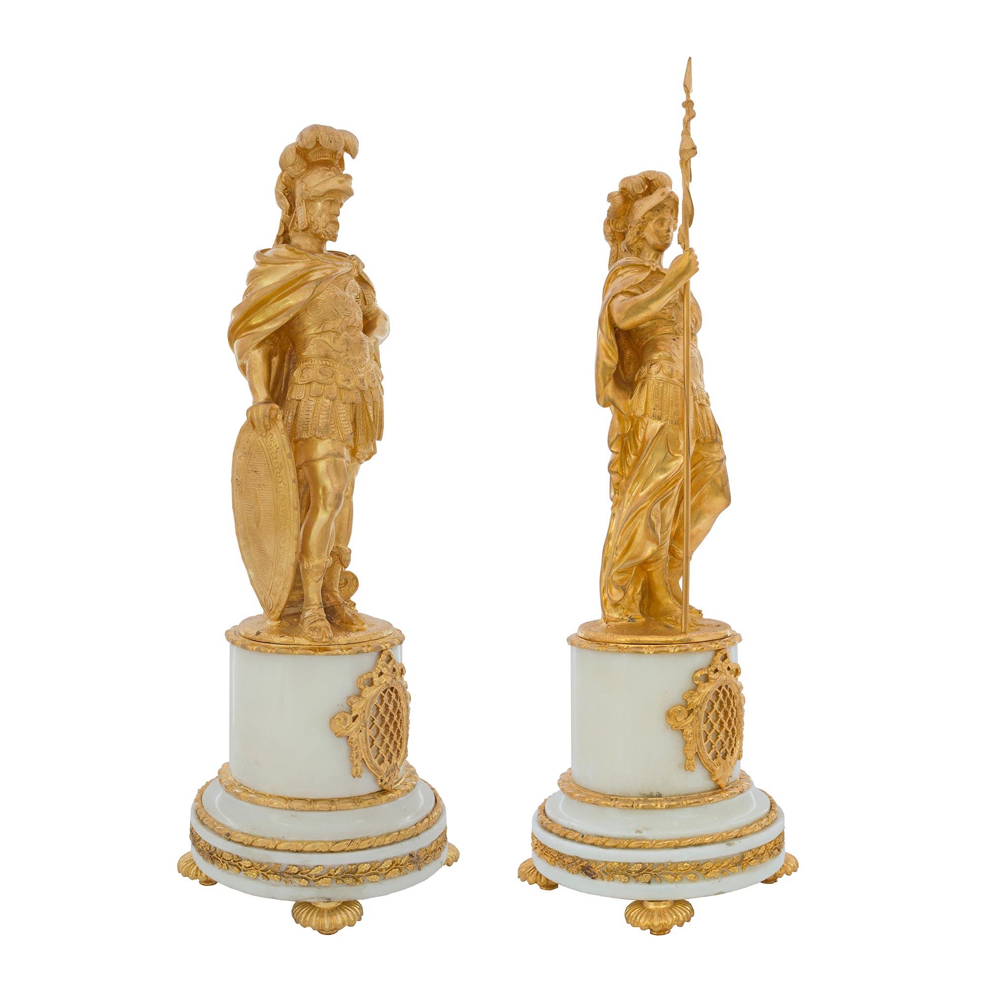A handsome pair of French Louis XVI st. 19th century statue depicting Mars and Minerva. Each statue is raised by a White Carrara circular pedestal above ormolu topie shaped supports. The pedestal is decorated by foliate and twisted bands under a