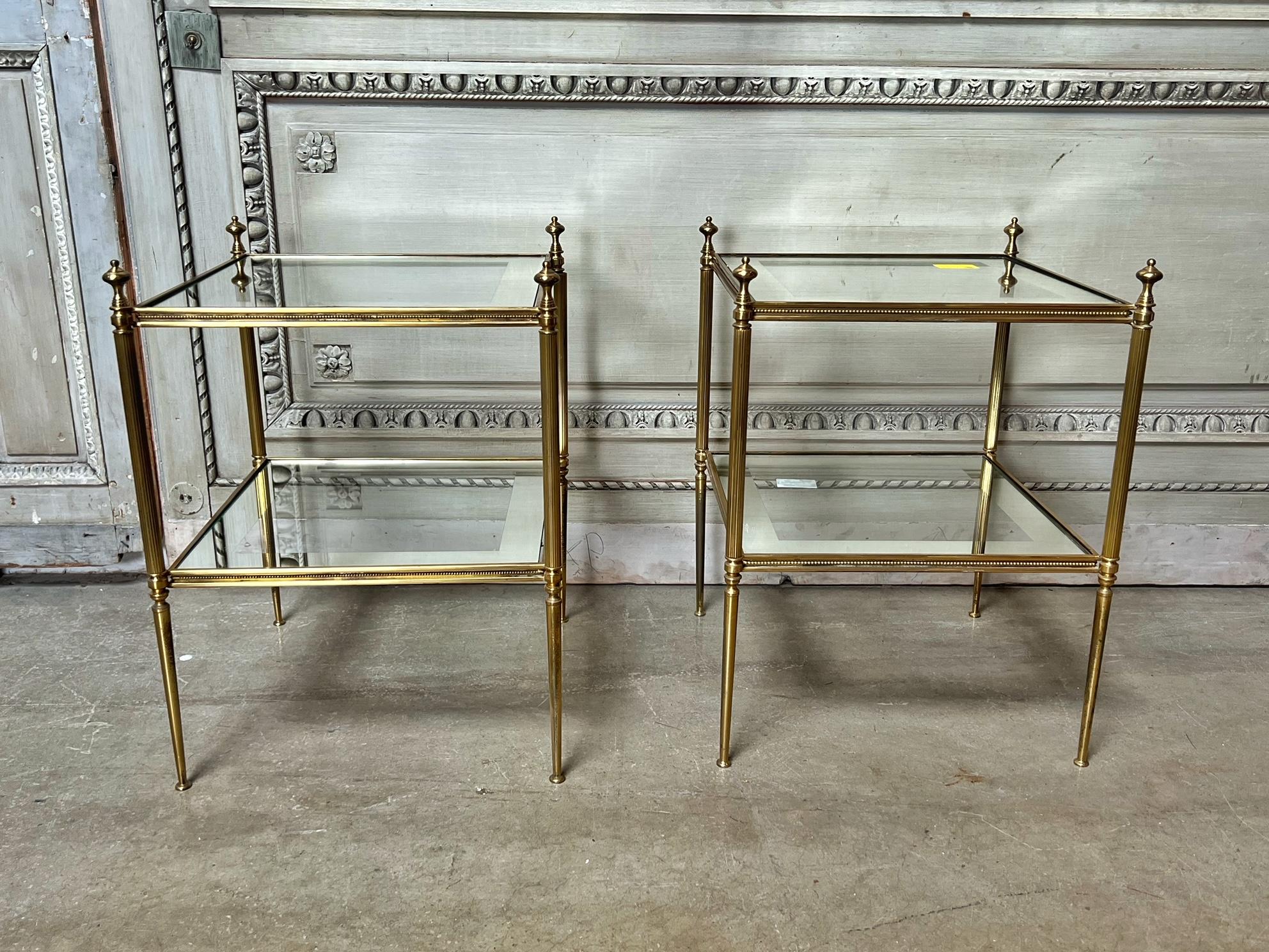 A pair of French polished brass tables with two tiers with glass and mirror tops These functional end tables are nice quality and very decorative and date from the mid to late 20th century.