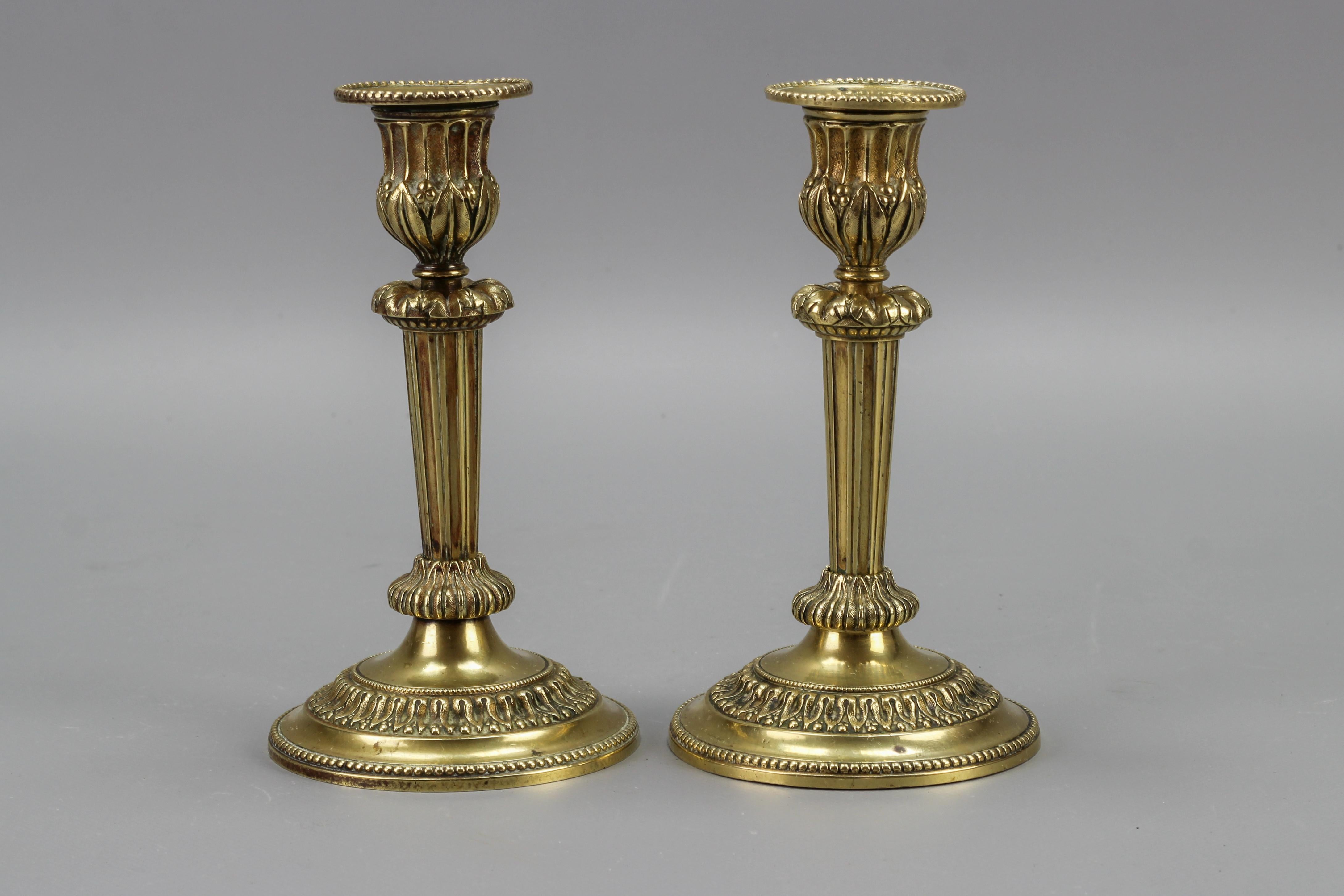 Ein elegantes Paar französischer Messing-Kerzenständer im Louis-XVI-Stil aus den 1920er Jahren. Diese hübschen und kompakten Kerzenhalter sind mit Blattmotiven verziert und haben einen spitz zulaufenden, kannelierten Schaft mit einem
