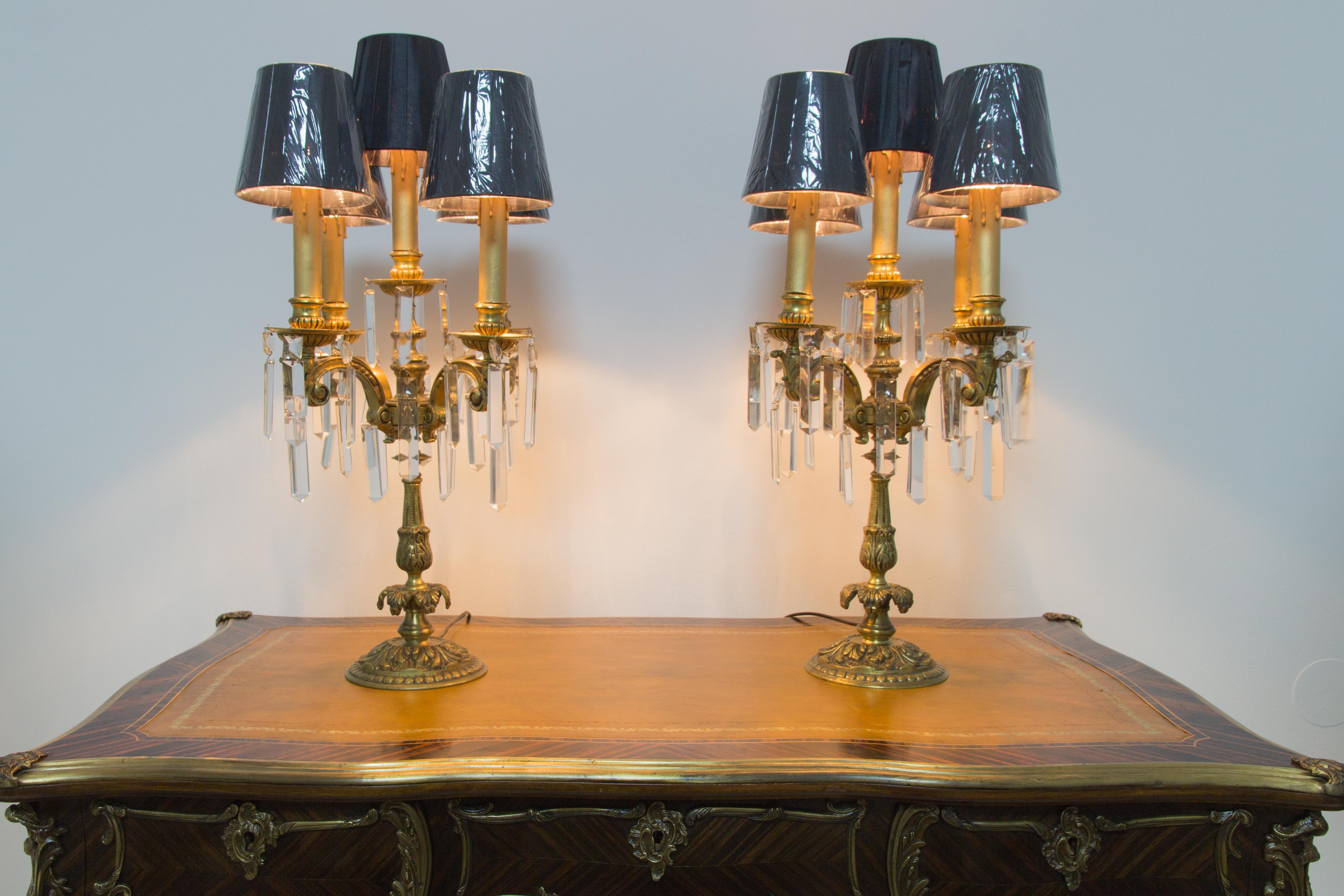 Pair of French Louis XVI style bronze and crystal candelabra table lamps. Each lamp has five bronze arms, embellished with hanging cut crystal prisms. Lamps have E14 size light bulb sockets and new black fabric lampshades. France, 1920s.
Each lamp