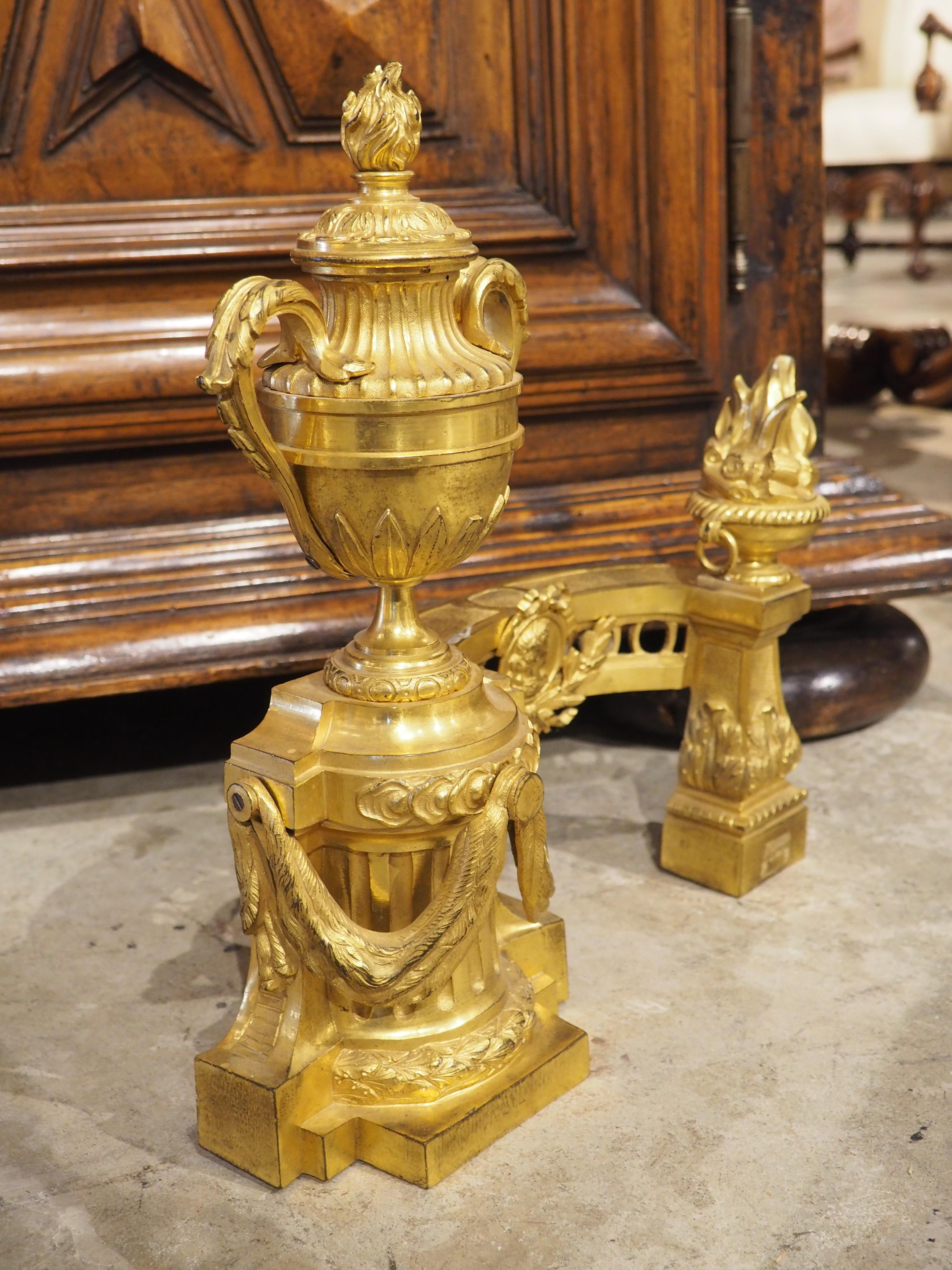 From France, circa 1850, this pair of bronze dore fireplace chenets are in the style of Louis XVI, as noted by the presence of multiple pots a feu finials. Chenets have been used for centuries to prevent burning logs from spilling out of the