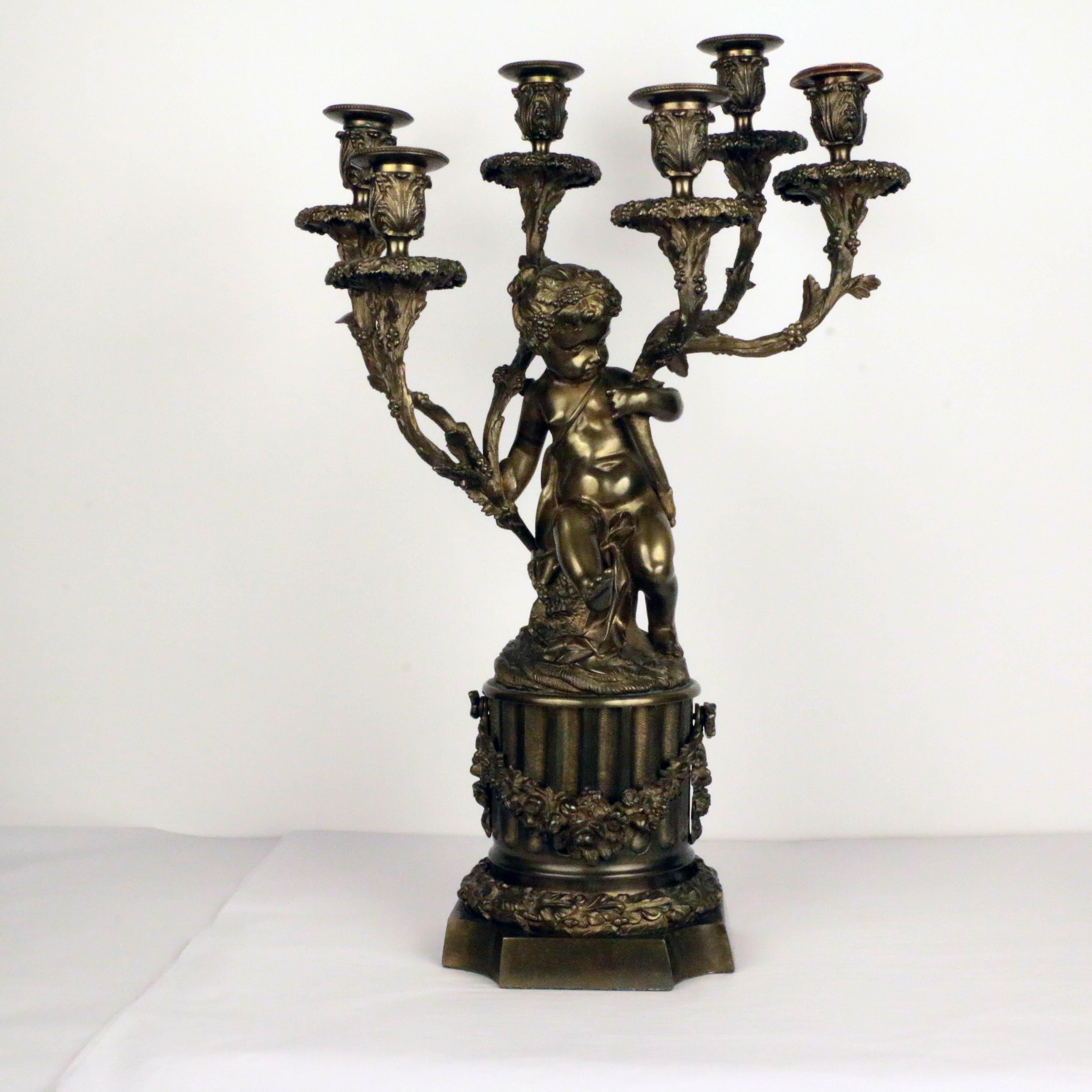 This imposing pair of bronze figural six-light candelabra, one modelled as a putto, the other as a satyr, is in the manner of Clodion.  Each is mounted on fluted and garlanded columns. This playful pair are crisply modelled with excellent