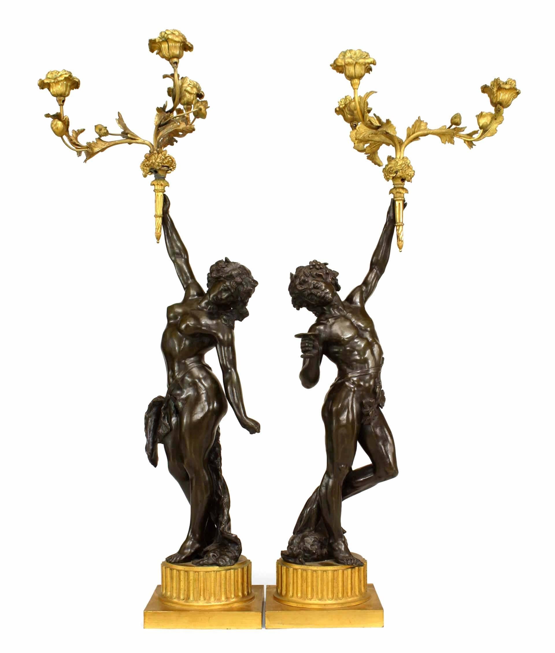 Pair of French Louis XVI style bronze figures of man and woman on gilt fluted base holding three-arm candelabra with floral design (19th century).
 