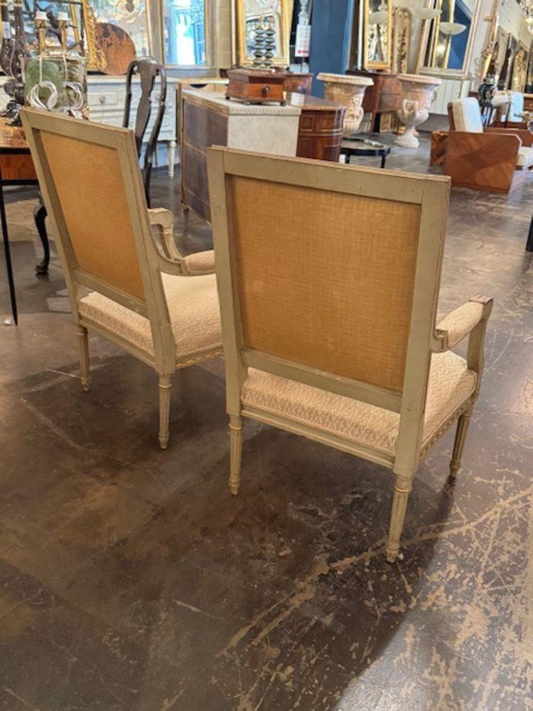 Esta pareja de sillones franceses de estilo Luis XVI presenta intrincados detalles tallados y parcelas doradas, que añaden un toque de lujo y elegancia a cualquier habitación. Como verdaderas antigüedades, estos sillones destilan estilo atemporal y