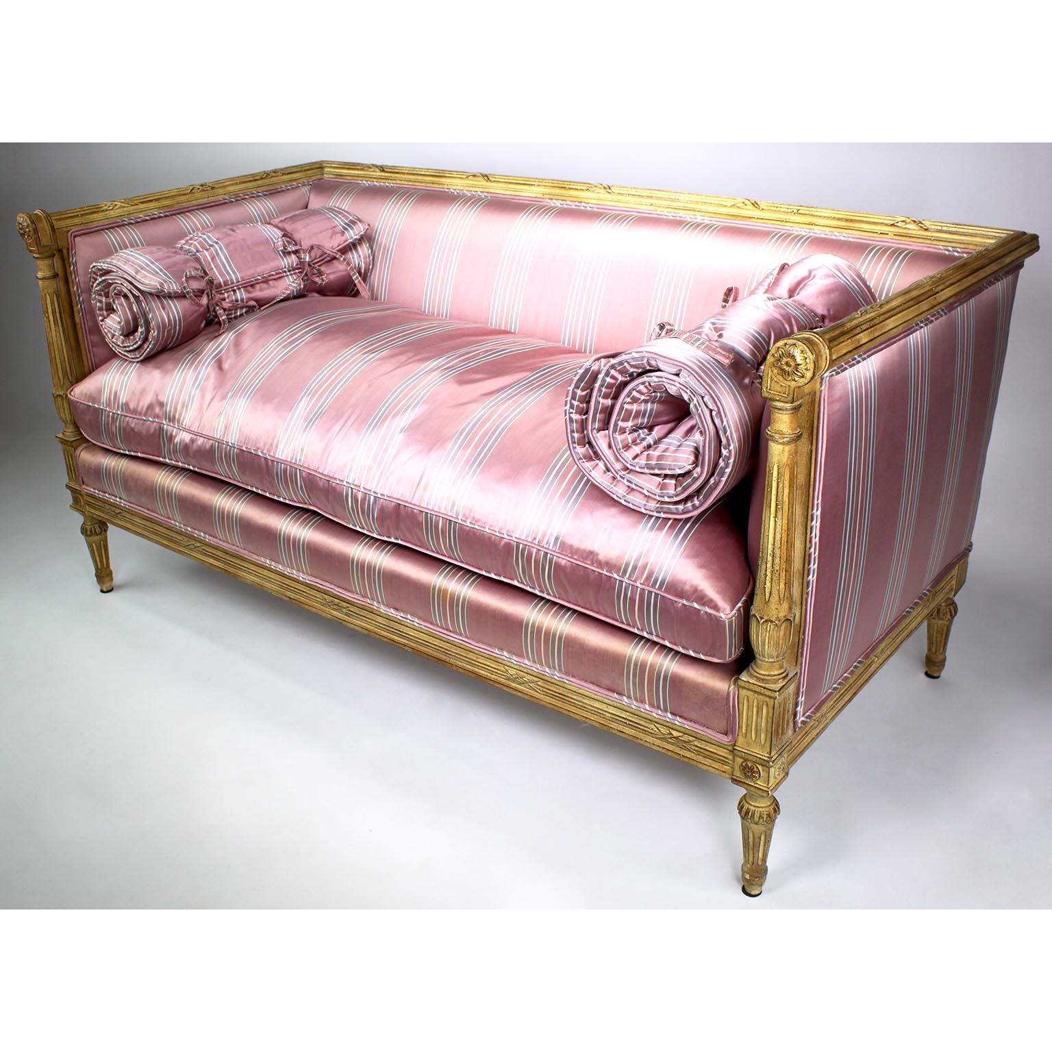 Paire de canapés français de style Louis XVI en bois sculpté laqué crème, probablement de la Maison Jansen. Les Love Seats de forme rectangulaire, chacun avec des accoudoirs sculptés à volutes se terminant par des rosettes, rembourrés sur tous les