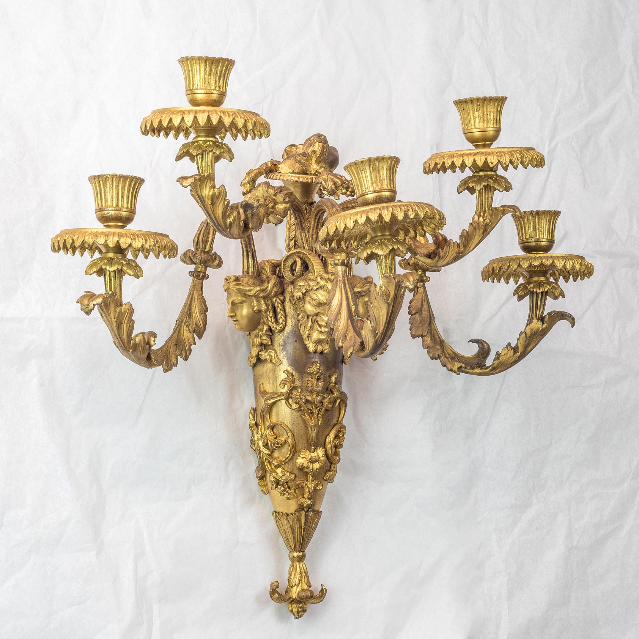 A fantastic pair of French Louis XVI style gilt bronze five-light wall sconces

Each with elongated oviform standard mounted with rocaille scrolls and surmounted by a saytr mask flanked by two female masks, issuing five acanthus scrolled candle