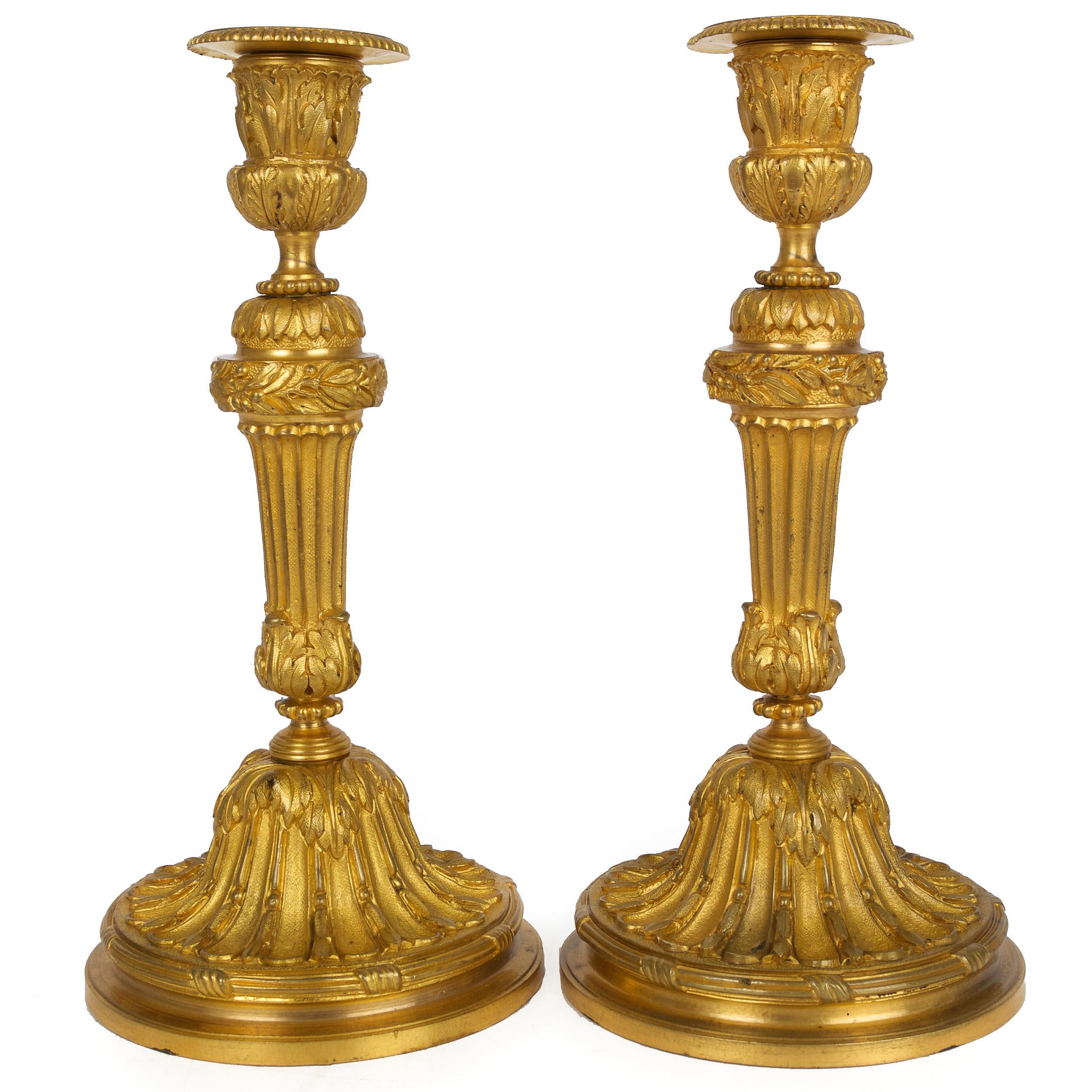A finely cast 19th century pair of Louis XVI style candlesticks executed in bronze with a brilliant ormolu surface, both are beautifully chiseled and chased. The separately cast drip-catch can be removed from the candle-well for cleaning, this cast