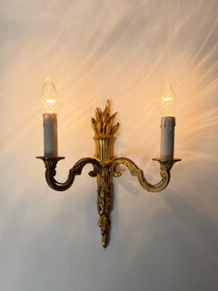 Par de apliques de pared dorados de estilo Luis XVI francés con detalles esculturales en forma de antorcha