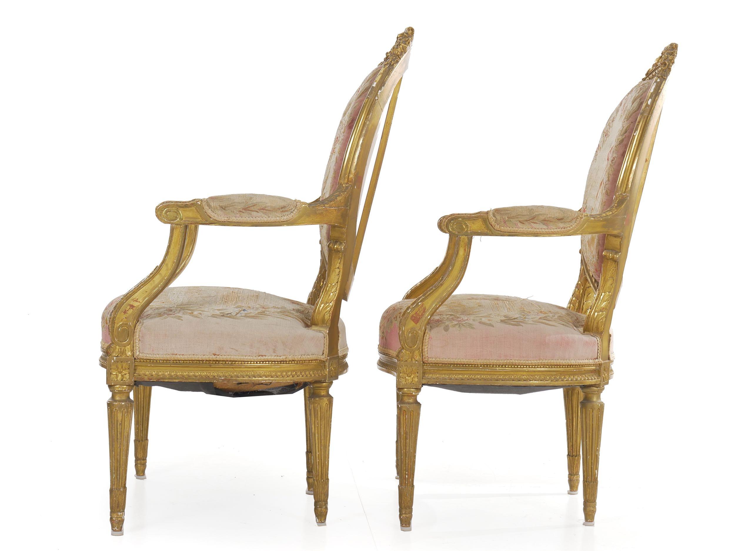A very nice early 20th century pair of giltwood fauteuils designed in the iconic Louis XVI taste, this beautiful pair of chairs exhibit crisp carved motifs and an attractively worn tapestry upholstery. The rich gilded and painted surfaces are