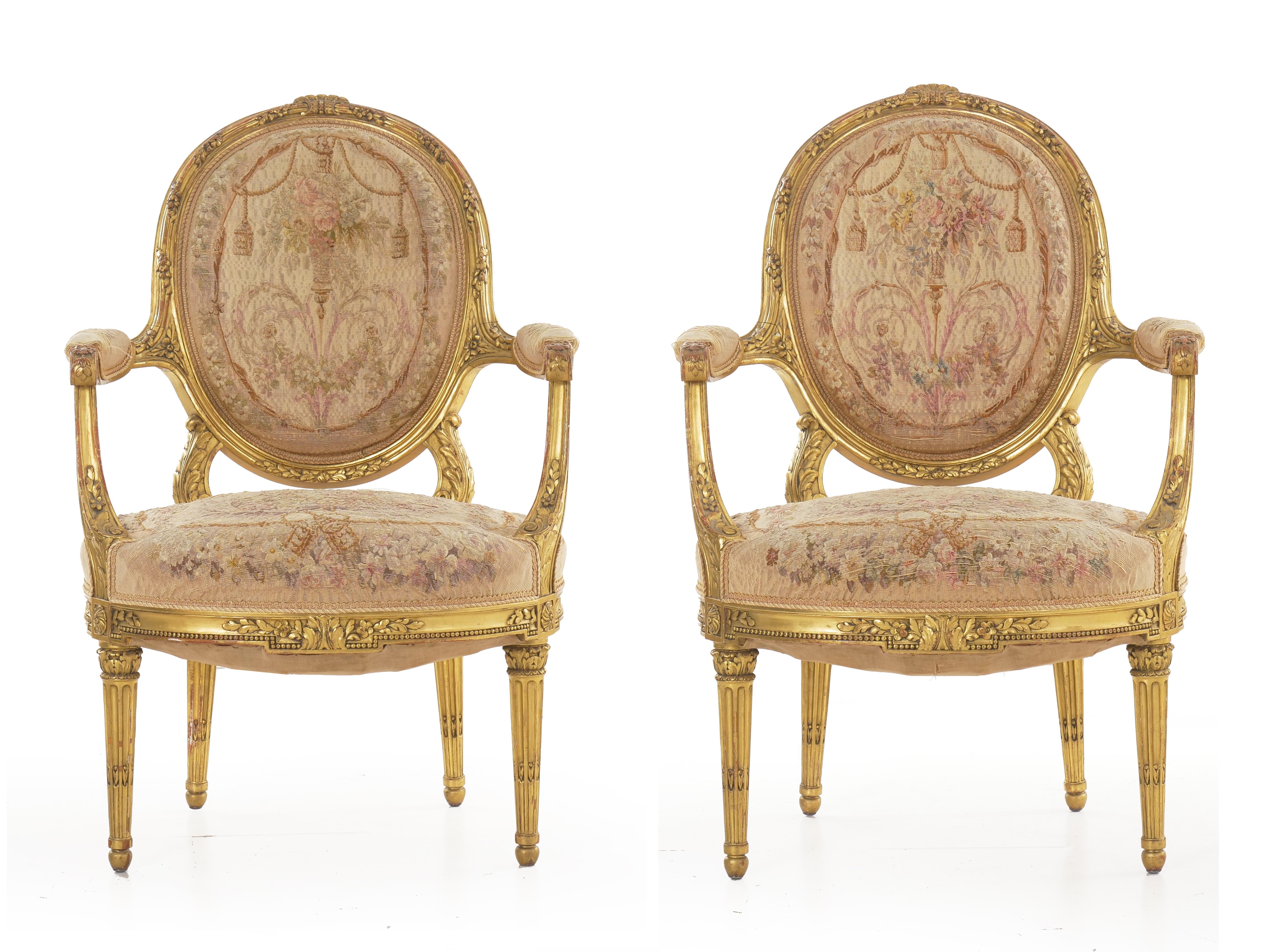 An exquisite pair of giltwood fauteuils designed in the iconic Louis XVI taste, this fine pair of chairs exhibit crisp carved motifs and an attractively worn tapestry upholstery. The rich gilded surfaces remain in overall good condition with a warm