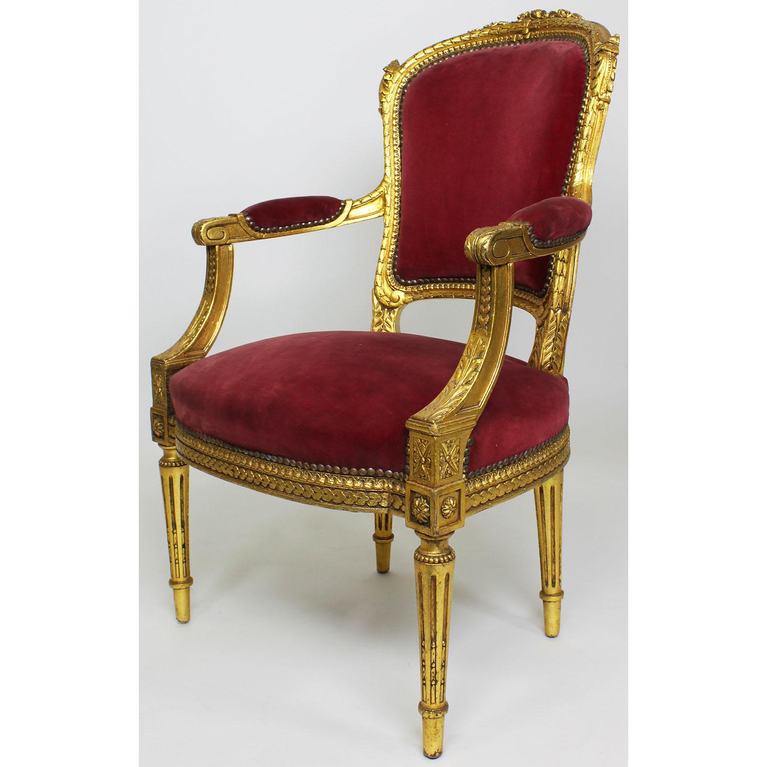 A pair of French Louis XVI style giltwood carved Rococo fauteuils (armchairs). The intricately carved wood frames with open and padded armrests and fluted legs. Upholstered in burgundy velvet Paris, circa 1900s.

Measures: Height 36 1/2 inches