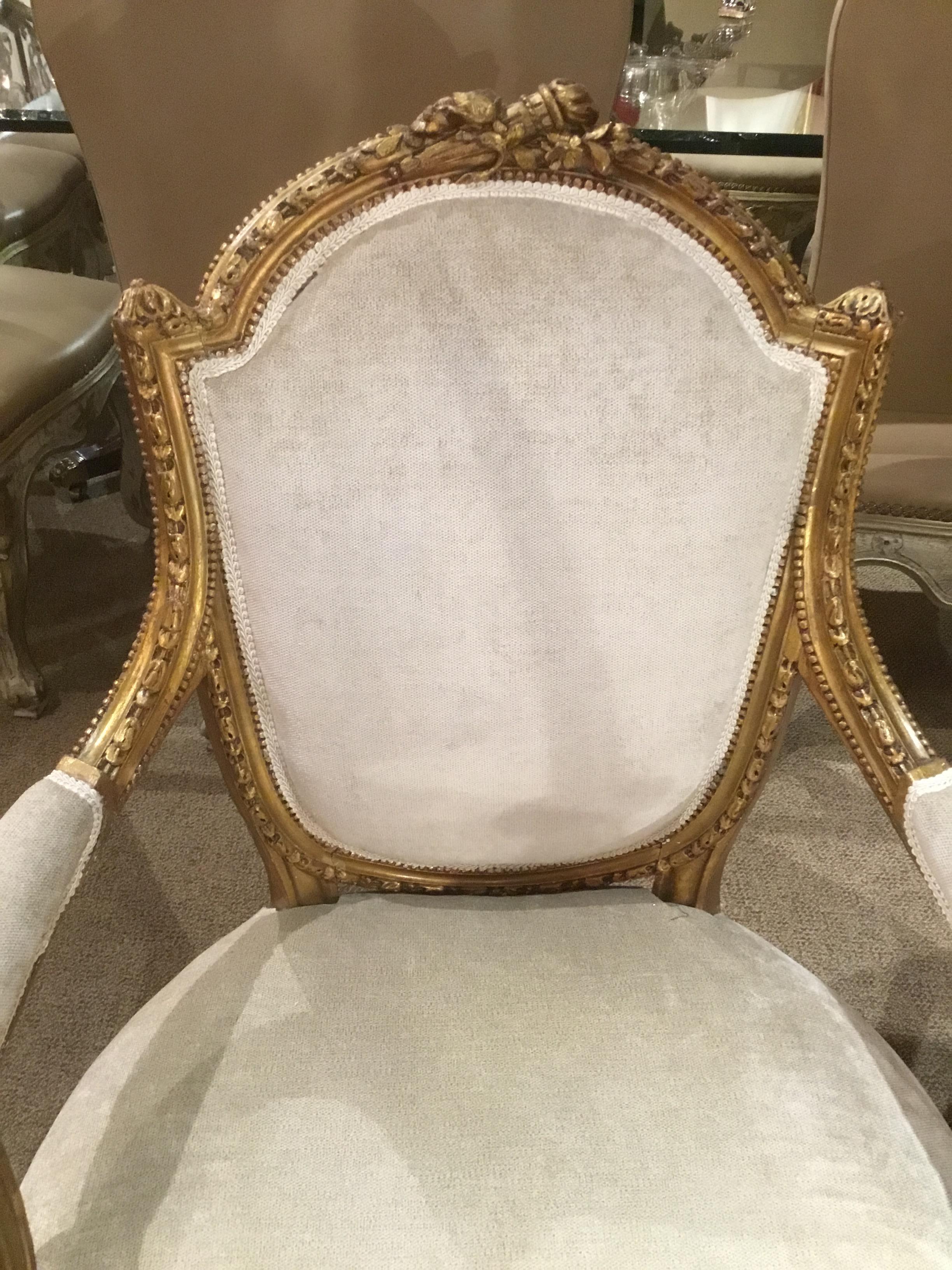 French Louis XVI style giltwood chairs with a flamed torch and foliate 
Design at the crest of these chairs. A carved and reeded leg is featured.