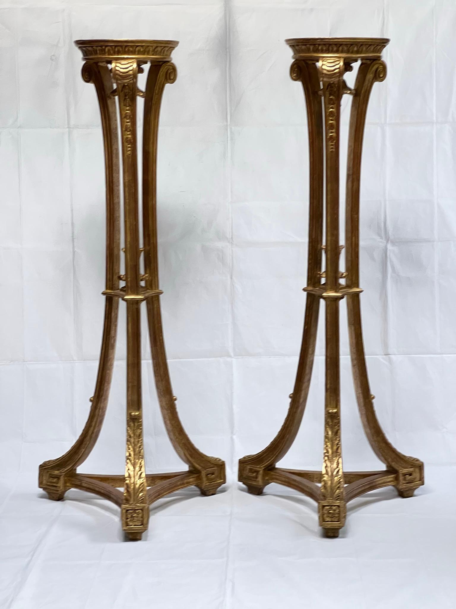 Pair of tall (47.5 inch) gilded wooden plant or candle stands with tripod base with neoclassical carved motifs including acanthus leaves, Greek keys and c-scrolls.  Circular tops measure 9 inches across.  