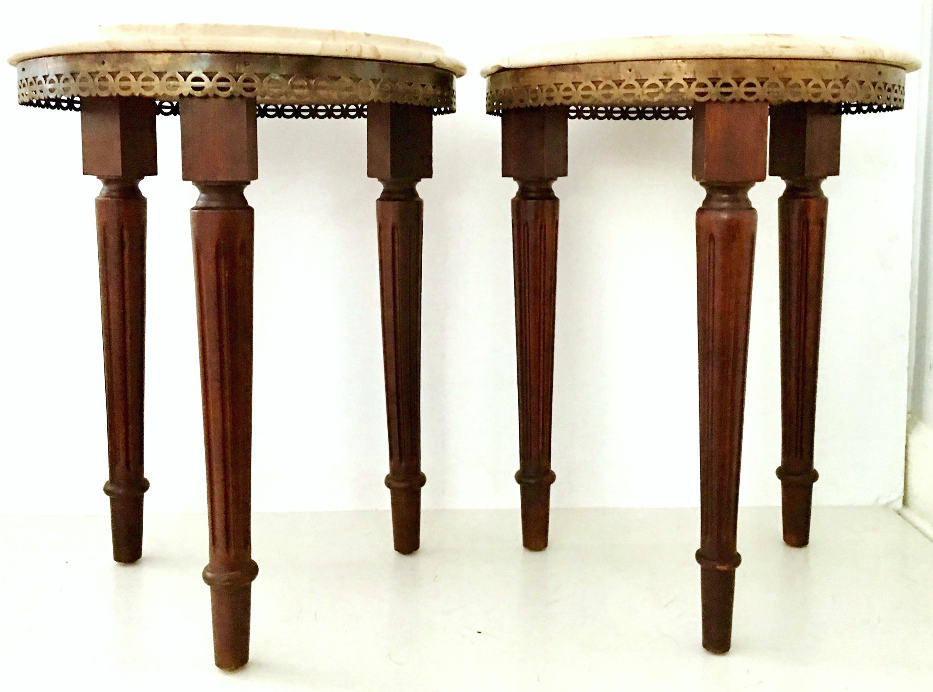 Pair Of 20th Century Signed French Louis XVI style Guerdion Mahogany and marble-top round side tables. These Classic tables feature fluted and turned legs a pierced geometric bronze gallery and beveled polished marble top in crema marfil. Signed on