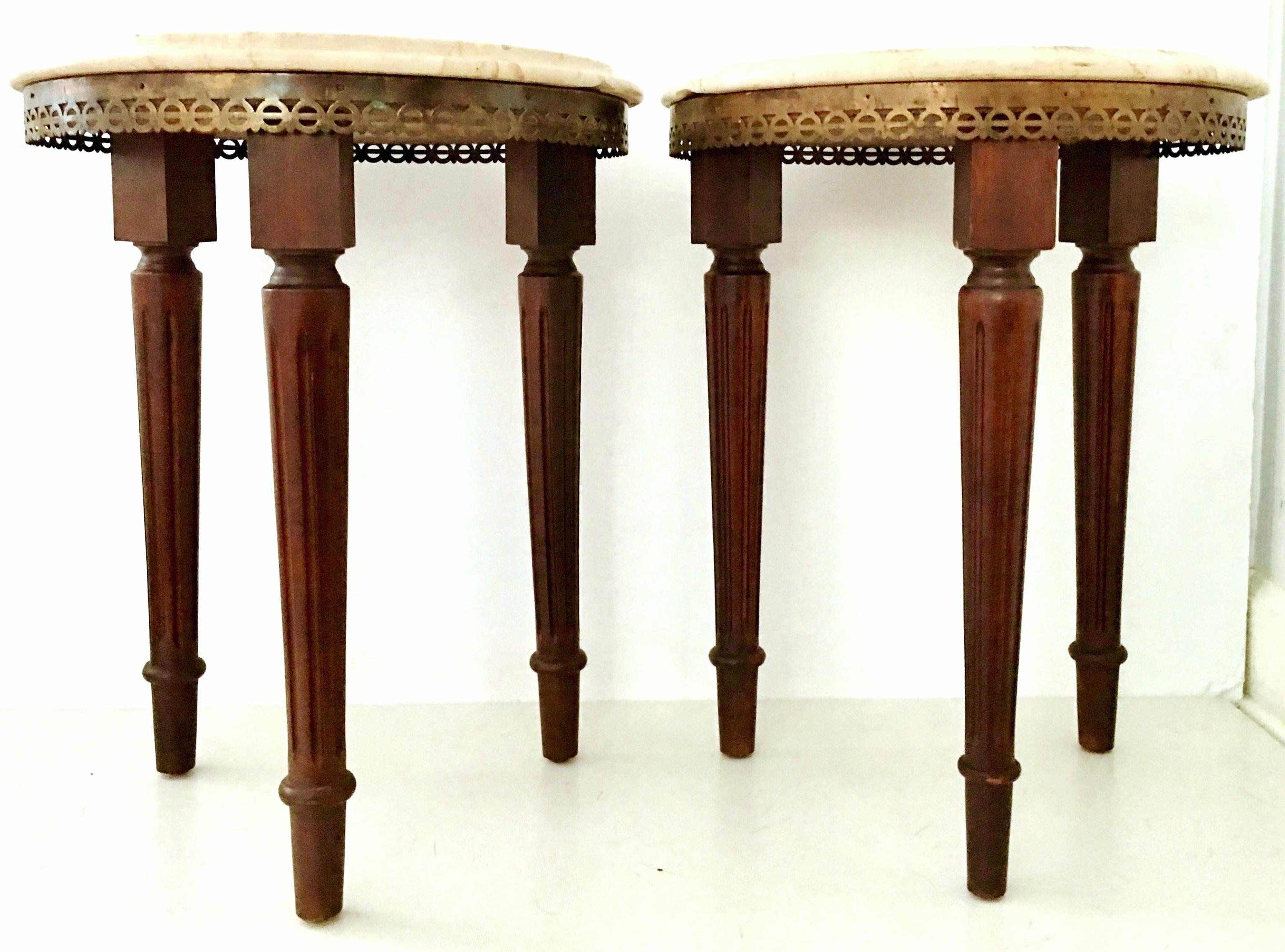 Pair of 20th century signed French Louis XVI style Guerdion mahogany and marble-top round side tables. These Classic tables feature fluted and turned legs a pierced geometric bronze gallery and beveled polished marble top in crema marfil. Signed on