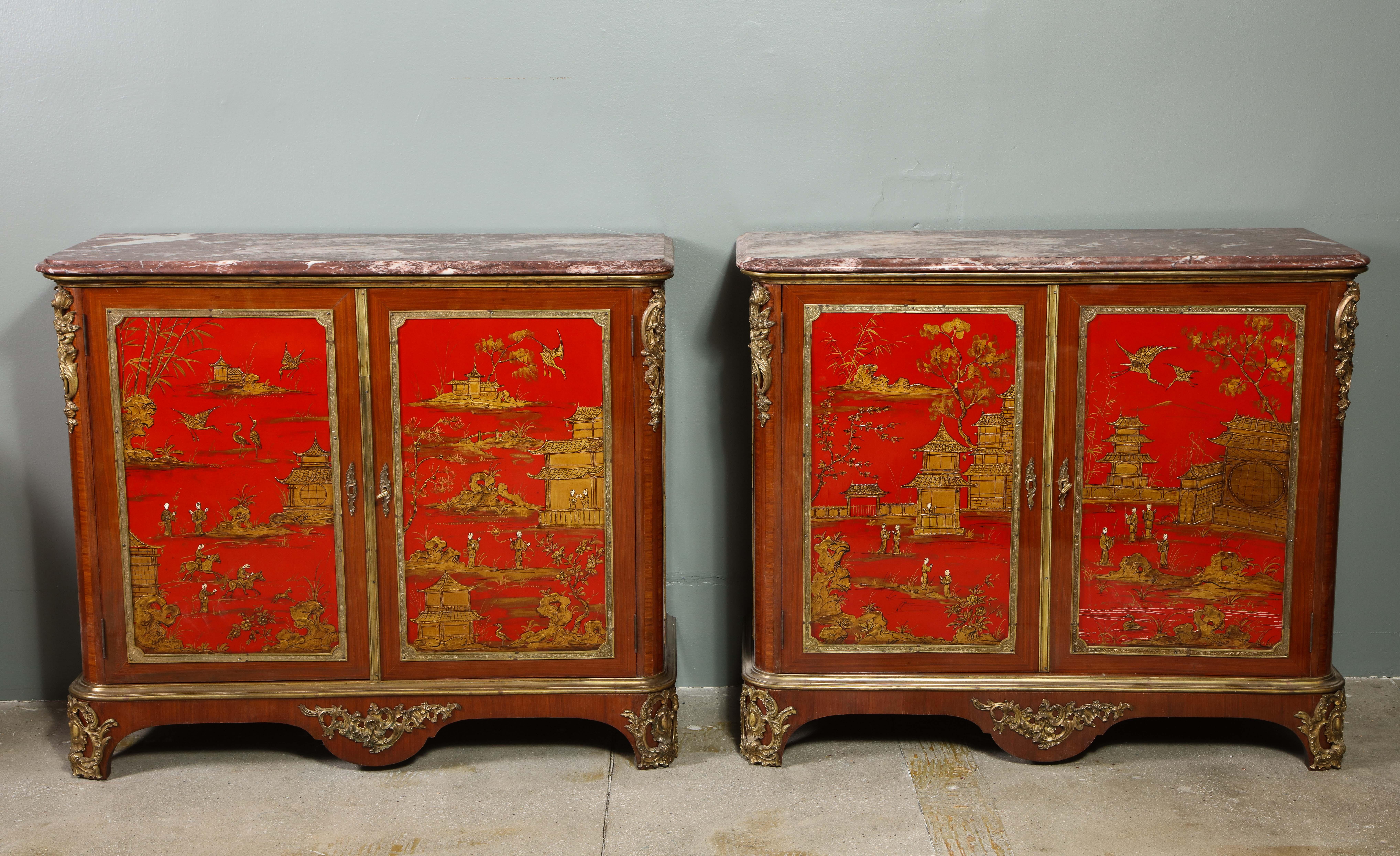 Chaque cabinet de chinoiserie laqué et monté sur bronze doré a un dessus en marbre, sur une paire de portes avec des panneaux de laque rouge encadrés de bronze, les côtés avec une décoration conforme, l'ensemble décoré sur toute la surface avec des