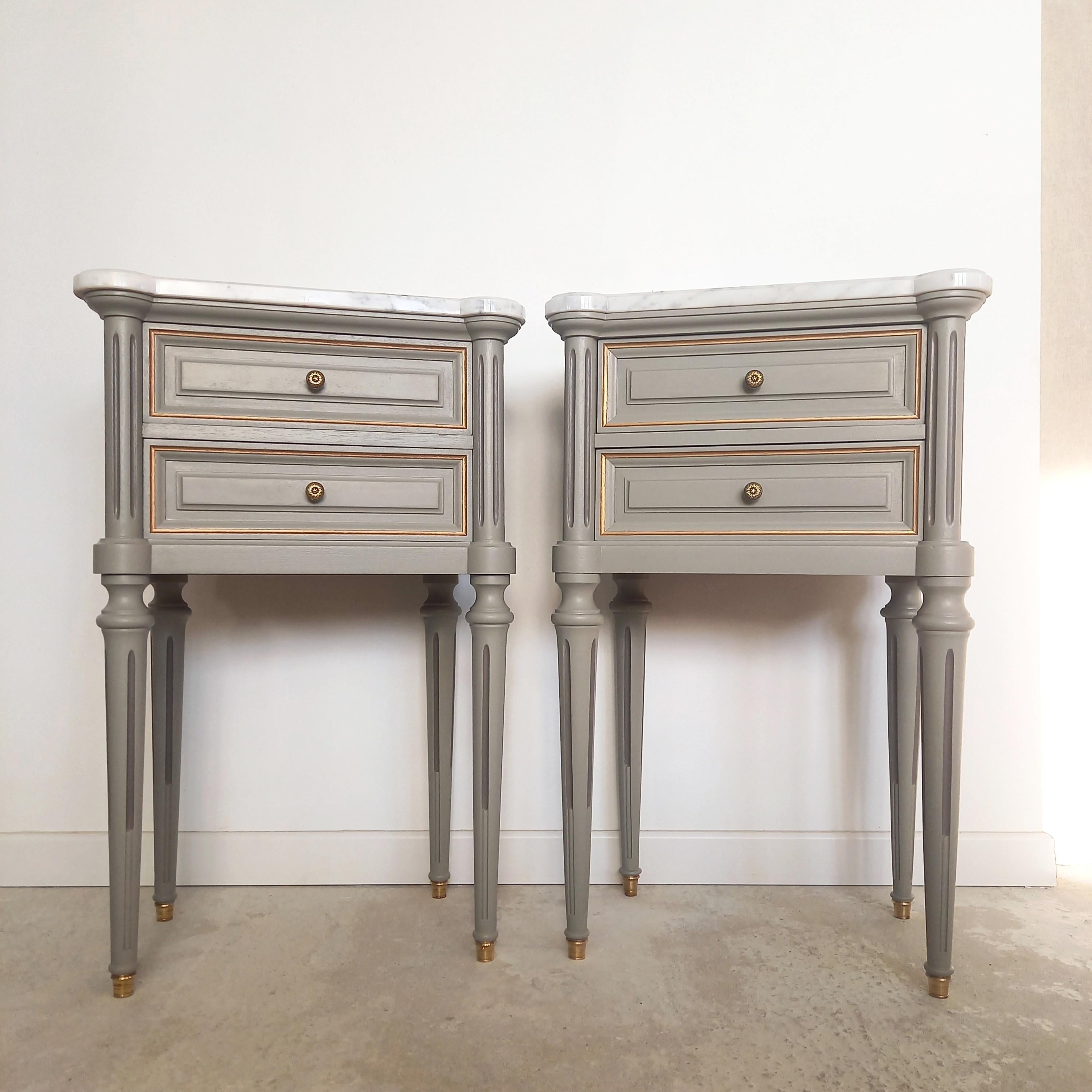 Antique French Louis XVI style pair of nightstands or side tables topped with a Carrara marble, legs finished with golden bronze clogs, with two dovetailed drawers.