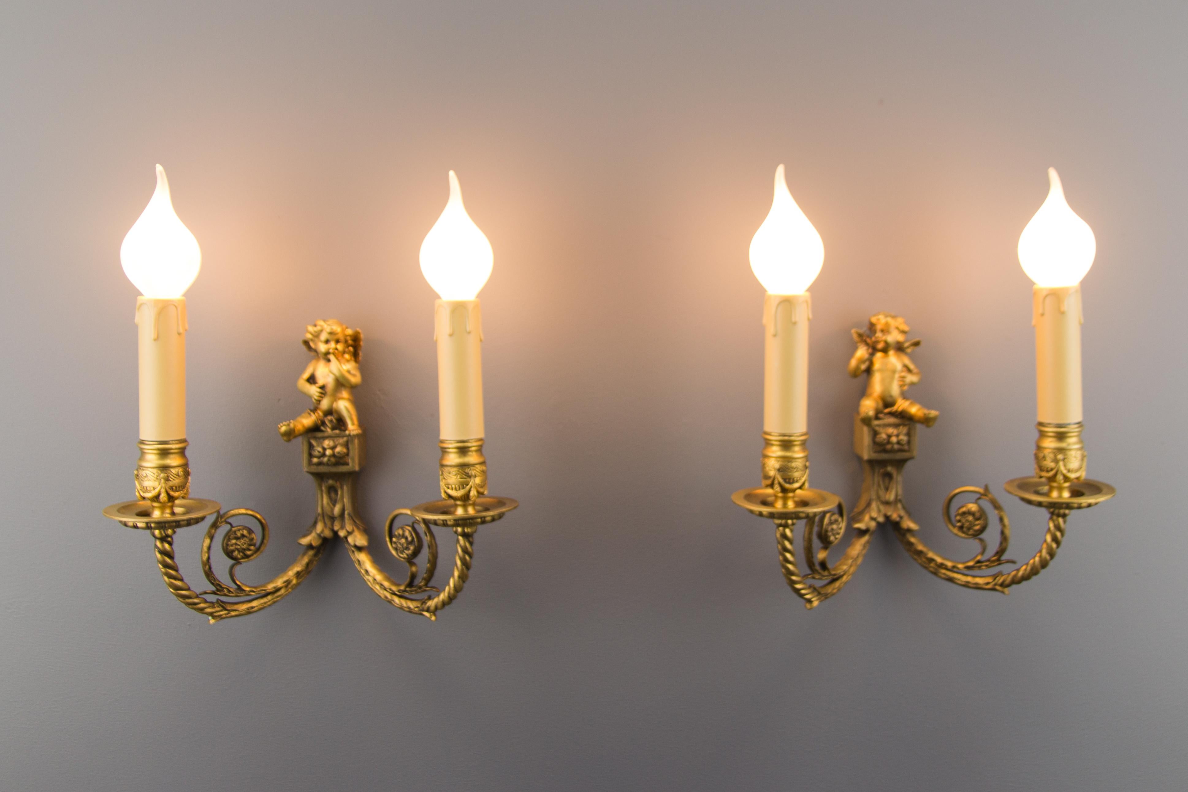 Lovely pair of late 19th century Louis XVI style French bronze cherub wall lights. These wall lights are electrified and each decorated with adorable winged cherub. Each sconce has two arms in the shape of ropes decorated with an interior ‘C’ scroll