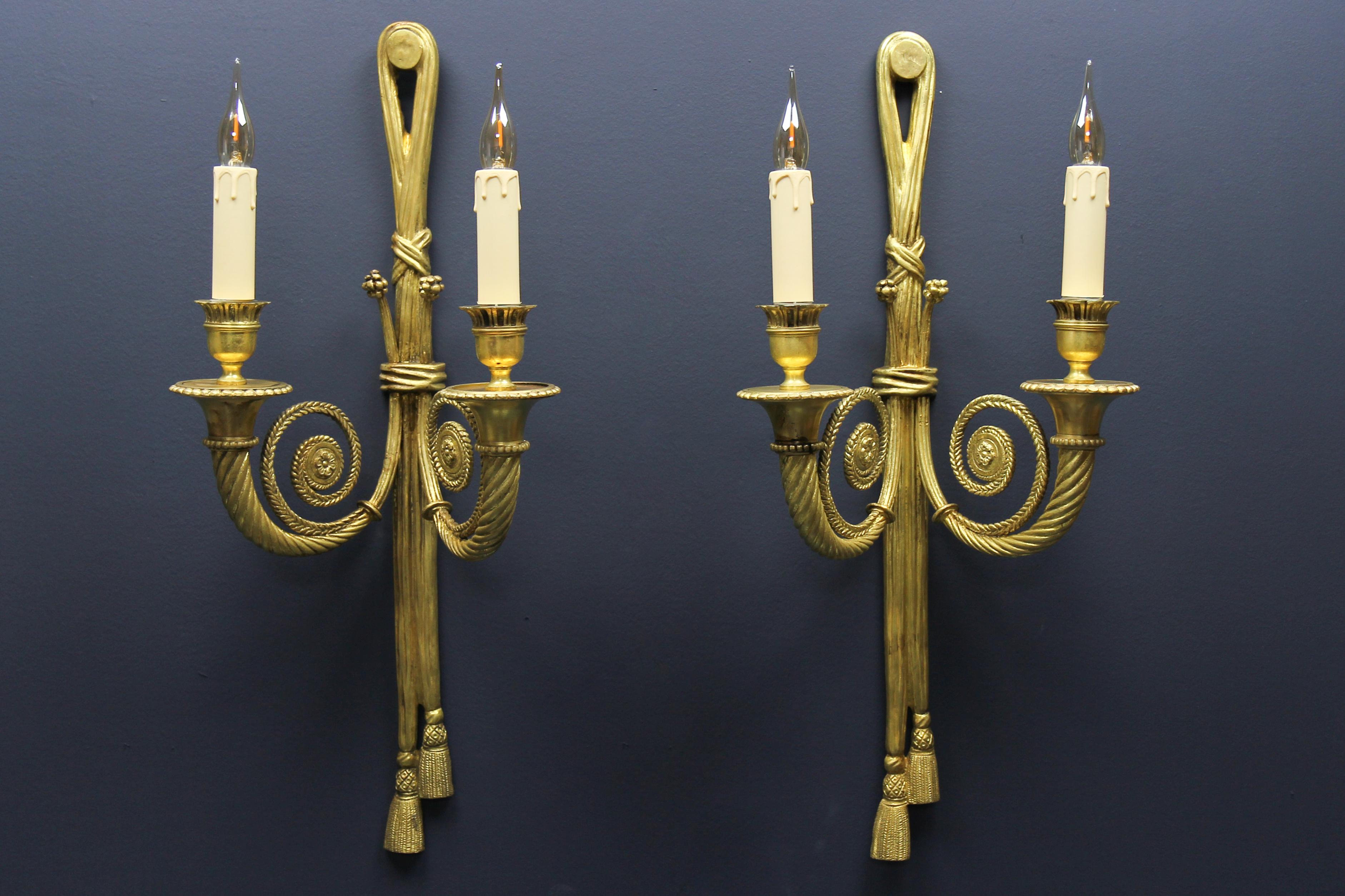 Pair of French Louis XVI style two-arm ribbon, knot, and tassel sconces, ca. 1910.
An elegant and large set of two Louis XVI or Neoclassical style bronze double-arm sconces from early 20th century, France. These impressive and beautiful sconces are