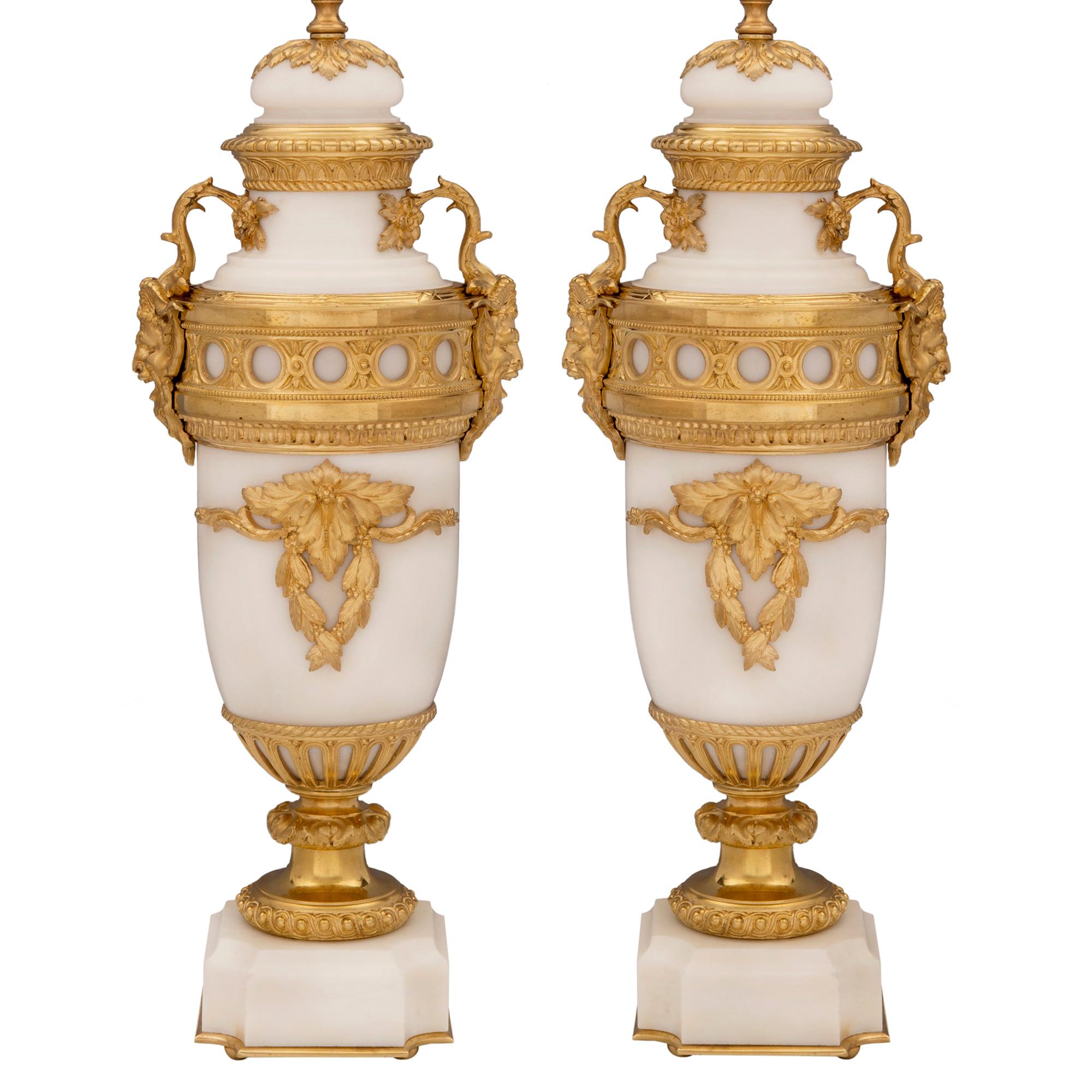 An extremely elegant pair of French 19th century Louis XVI st. white Carrara marble and ormolu lamps. Each lamp is raised by fine discreet ball feet below a square white Carrara marble base with a mottled top. concave corners and a decorative ormolu