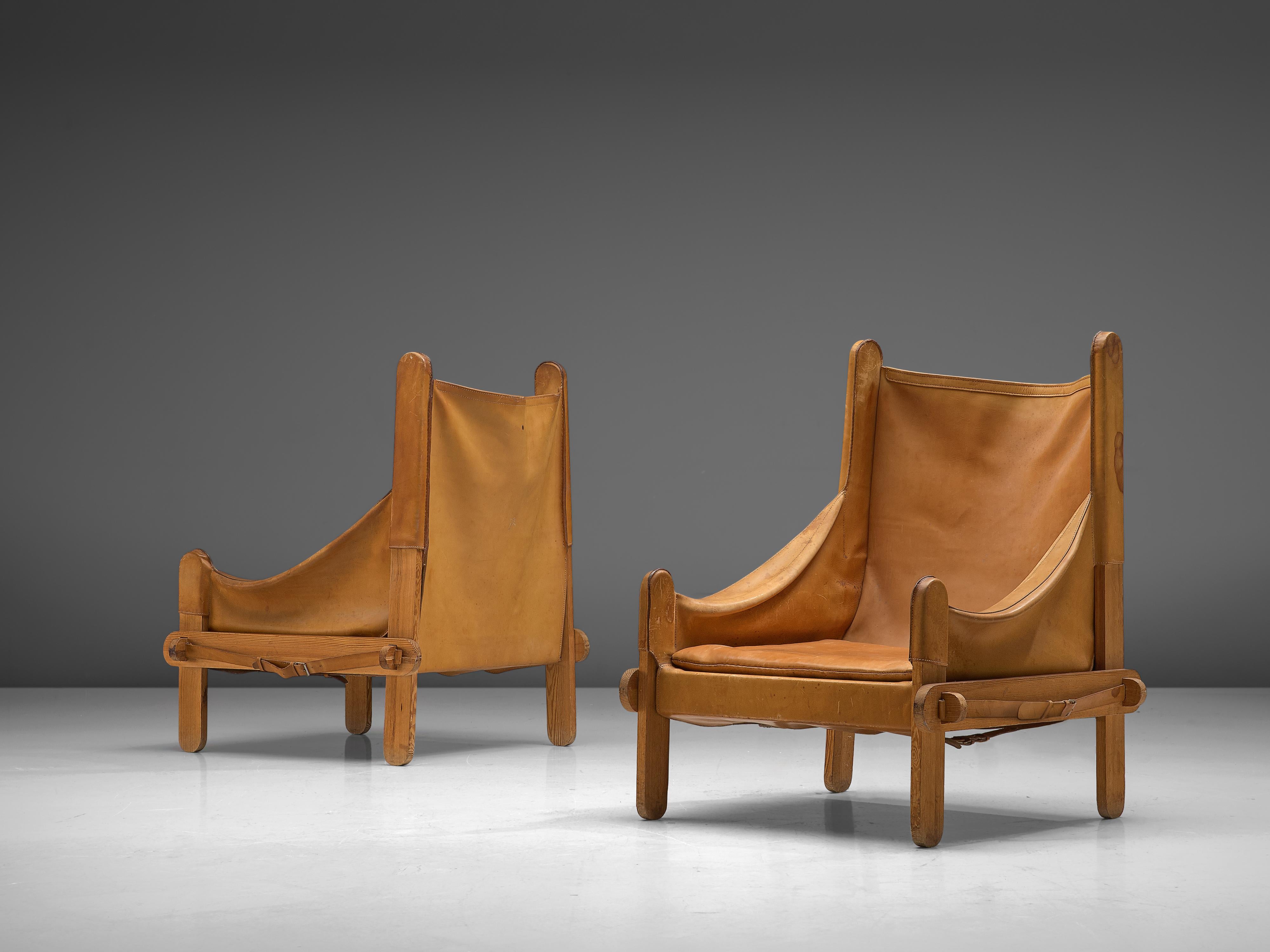 Pair of lounge chairs, leather, wood, metal, France, 1950s

These lounge chairs are characterized by the patinated cognac leather that is adjusted to the wooden frame consisting of wooden slats with round ends. The warm colored leather is attached