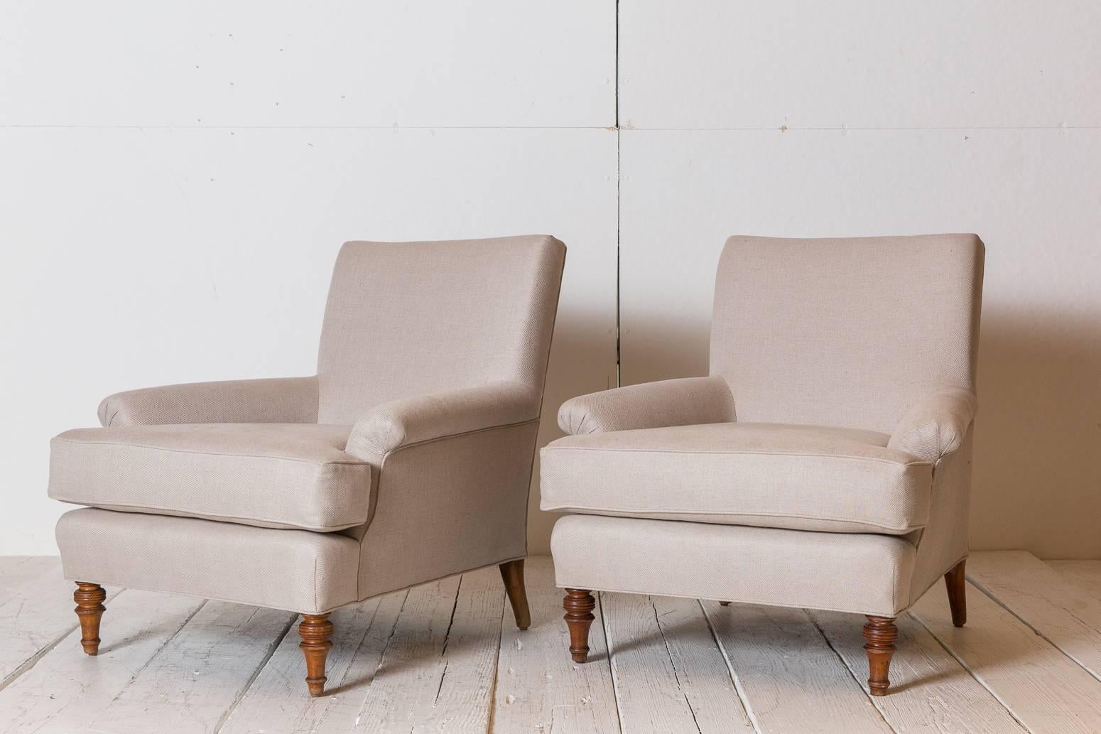 Pair of French lounge chairs newly upholstered in natural linen with oak turned legs.