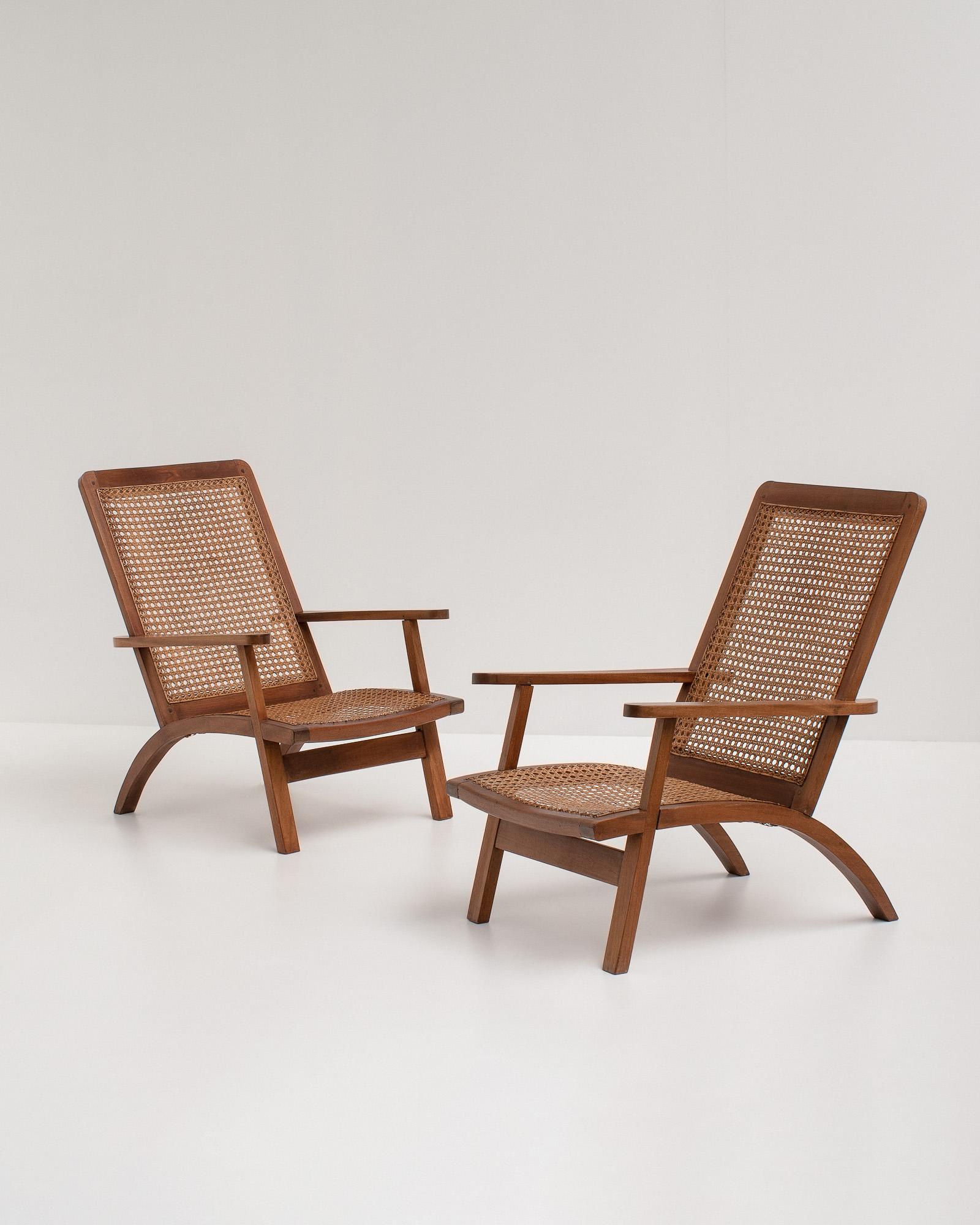 A pair of stunning mid-century sculptural French armchairs in mahogany with caned seating and back, France, 1950s. 
The seat and backs are made of cane and the simple detailing and craftsmanship elevate the design of these chairs. 

They have a