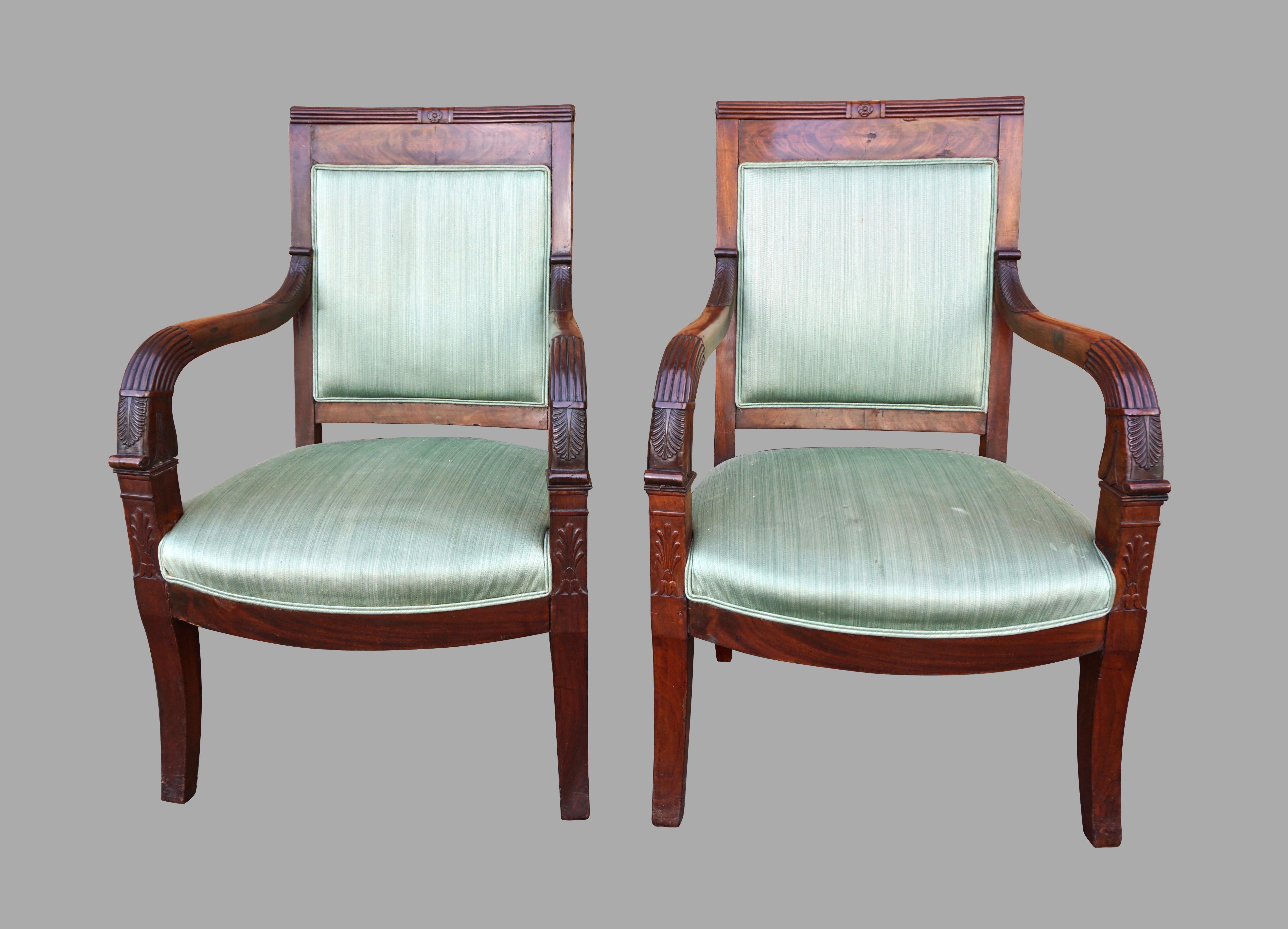 A pair of French Charles X period mahogany armchairs of typical form, the crest rails with a reeded upper edge and central carved detail, the reeded down swept arms with a well-carved stylized acanthus leaf decoration, supported on slightly curved