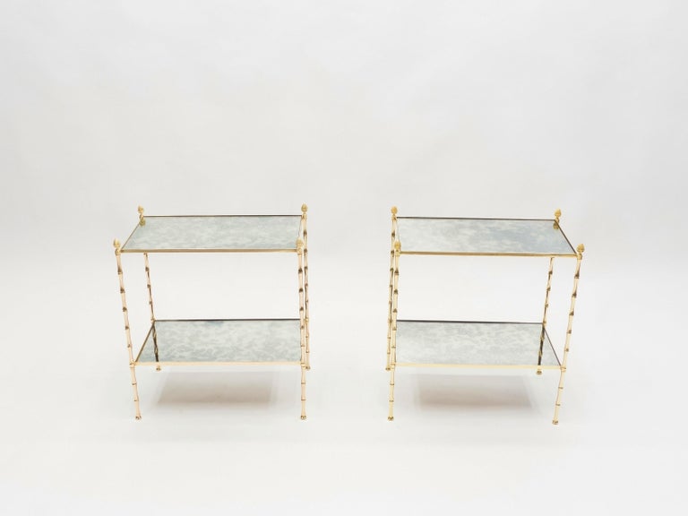 This pair of two-tier end tables by French design house Maison Baguès was created with solid bamboo shaped brass, typical French neoclassical pine cone, and beautiful old patina mirror, circa 1960. The two-tier mirrors are timeless and smooth,