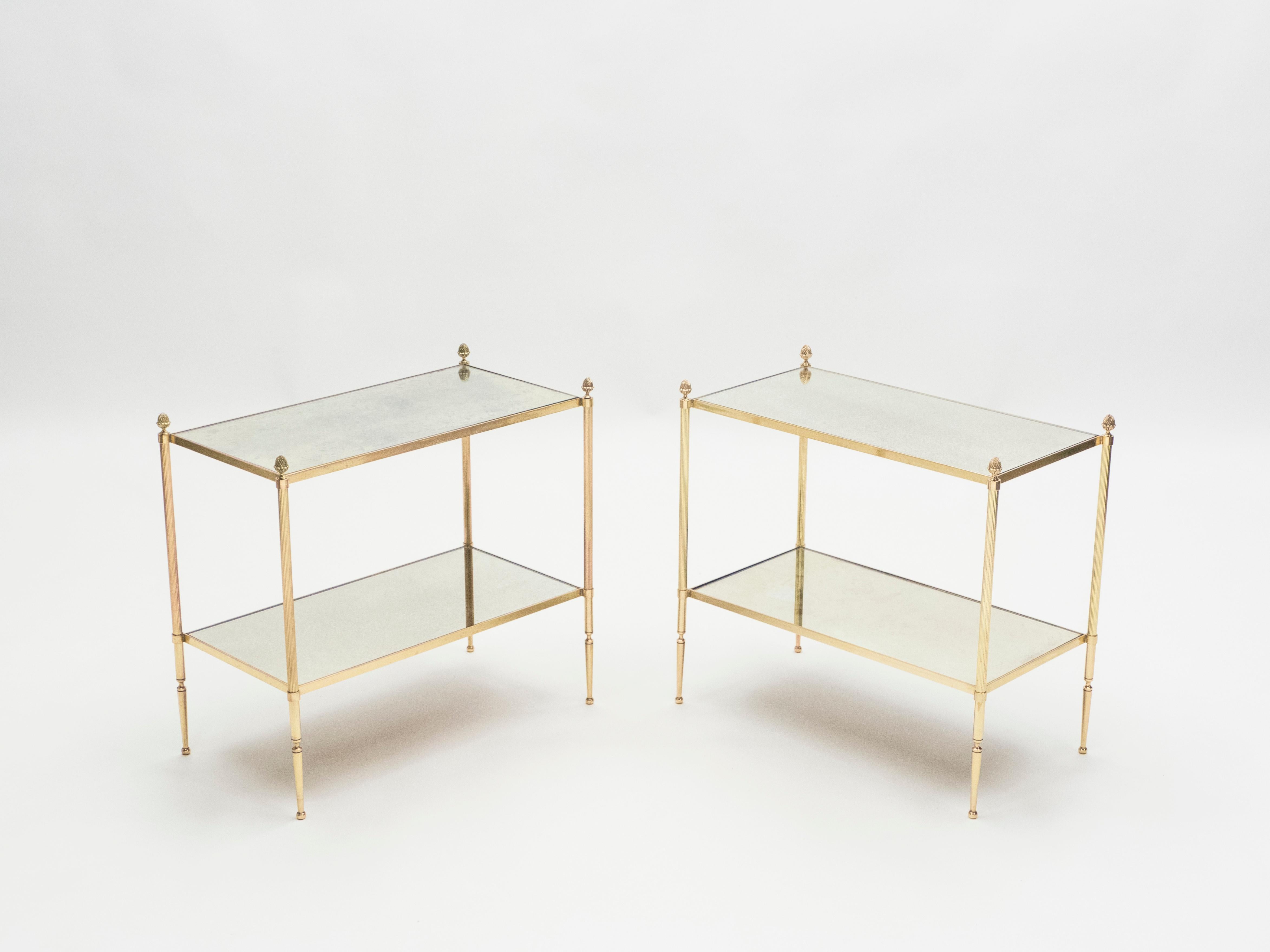 This pair of two-tier end tables by French design house Maison Baguès was created with solid brass, typical French neoclassical pine cone, and beautiful old patina mirror, circa 1950. The two-tier mirrors are timeless and smooth, while the brass