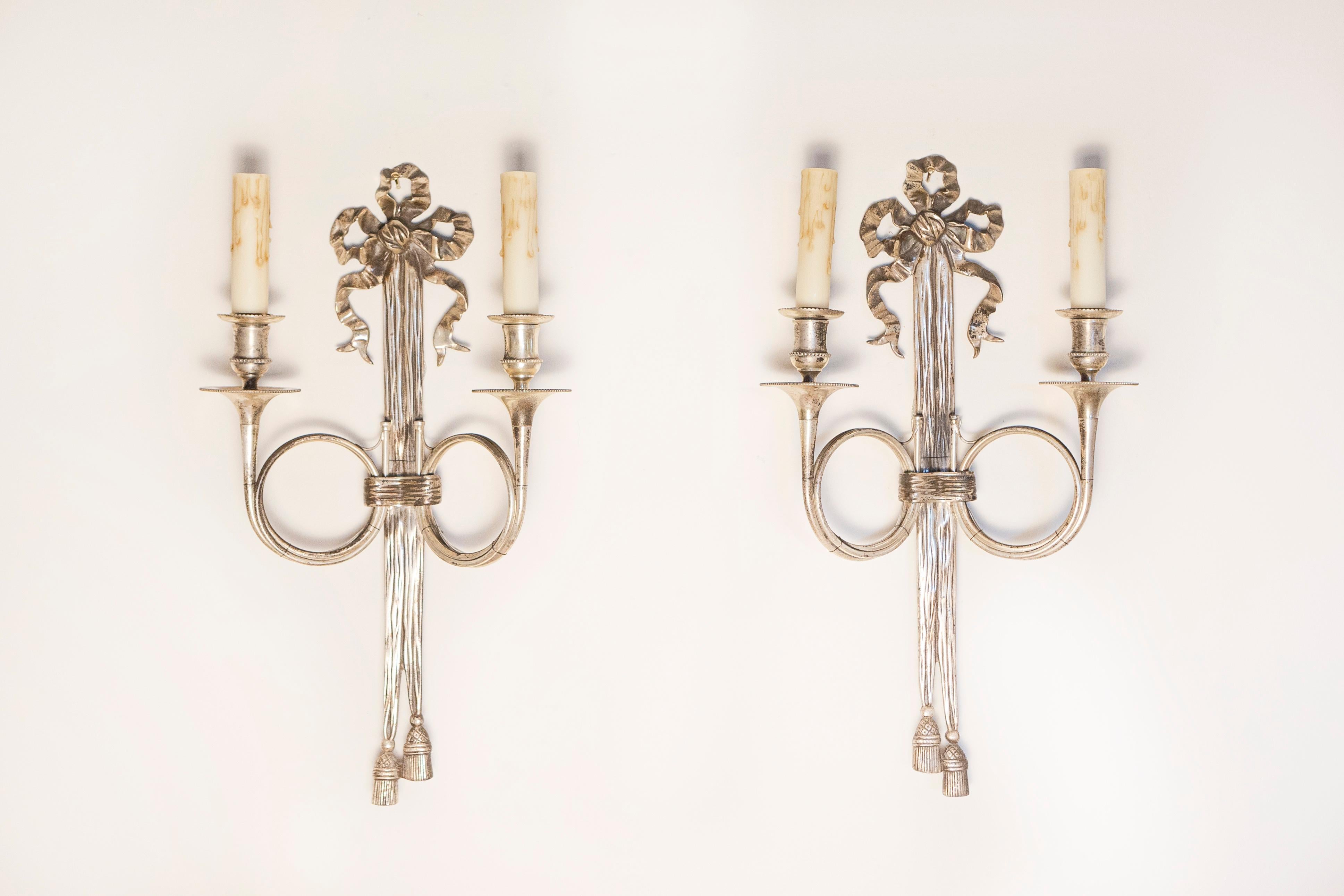 Coppia di applique in bronzo argentato in stile Maison Baguès francese degli anni '60 con nastri e corni da caccia francesi. Questa raffinata coppia di applique francesi in bronzo argentato ispirate alla Maison Baguès degli anni '60 cattura