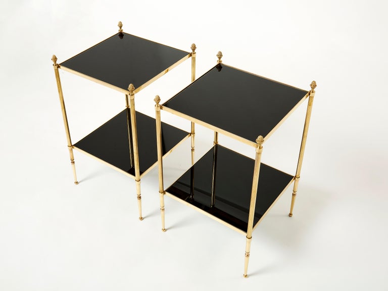 This pair of two-tier end tables by French design house Maison Jansen was created with solid brass, typical french neoclassical pine cone, and beautiful black opaline glass tops circa 1960. The two-tier black tops are timeless yet modern, while the