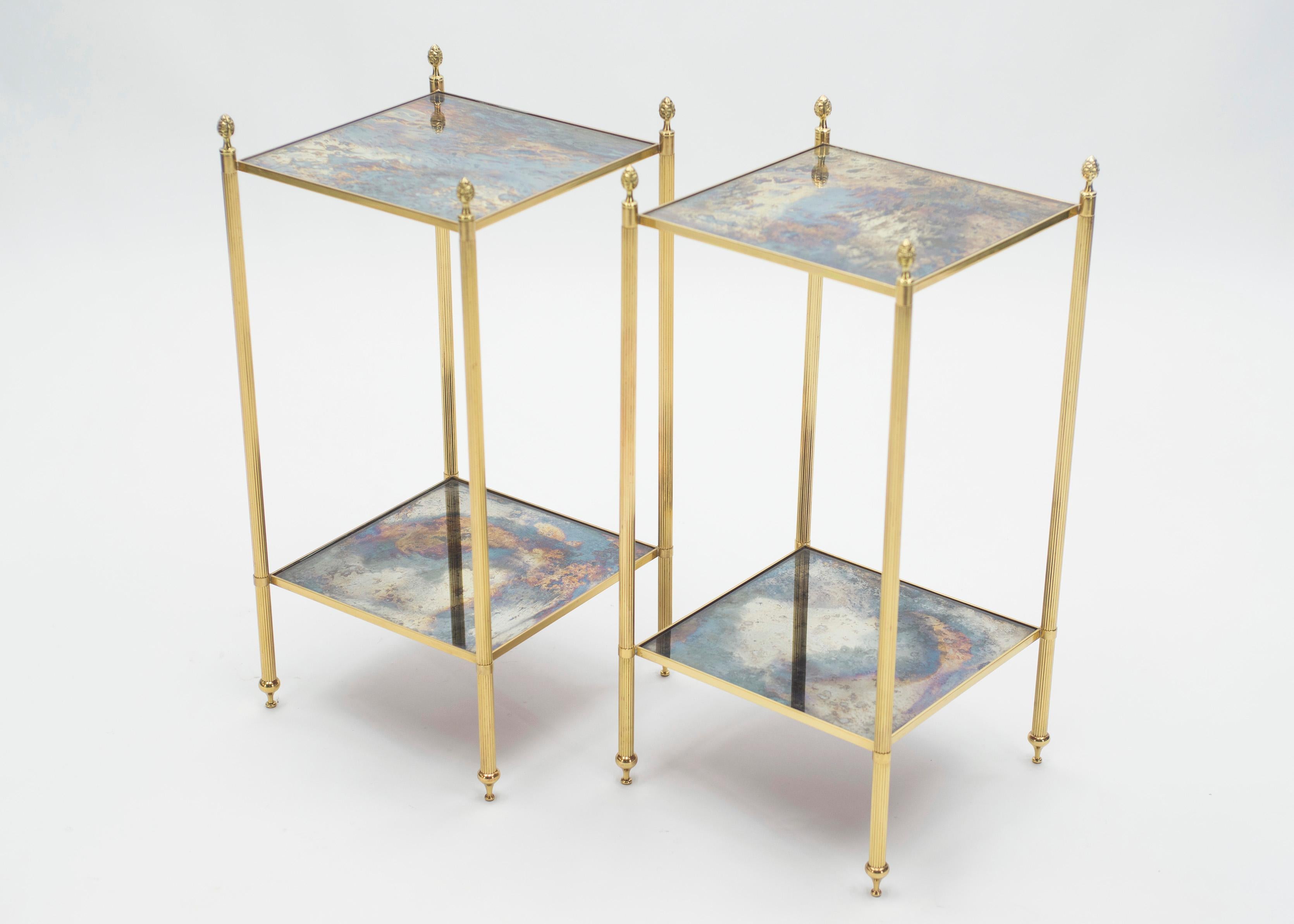 This pair of two-tier end tables by French design house Maison Jansen was created with solid brass, typical French neoclassical pine cone, and beautiful old patina mirror, circa 1960. The two-tier mirrors are timeless and smooth, while the brass