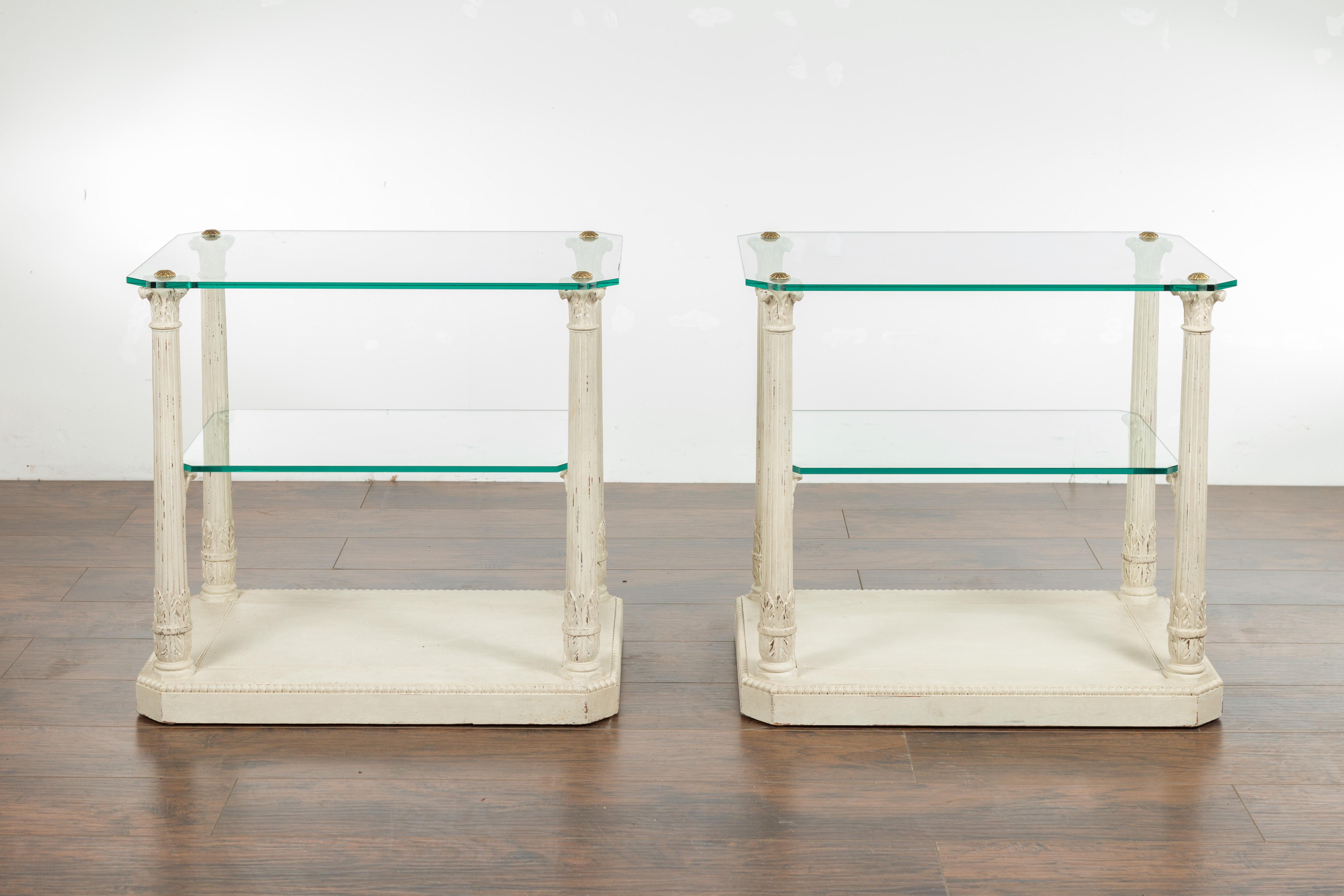 A pair of French Maison Jansen column tables from the mid-20th century, with Corinthian capitals and glass top and shelves. Created in France during the midcentury period, each of this pair of Maison Jansen tables features a rectangular glass top