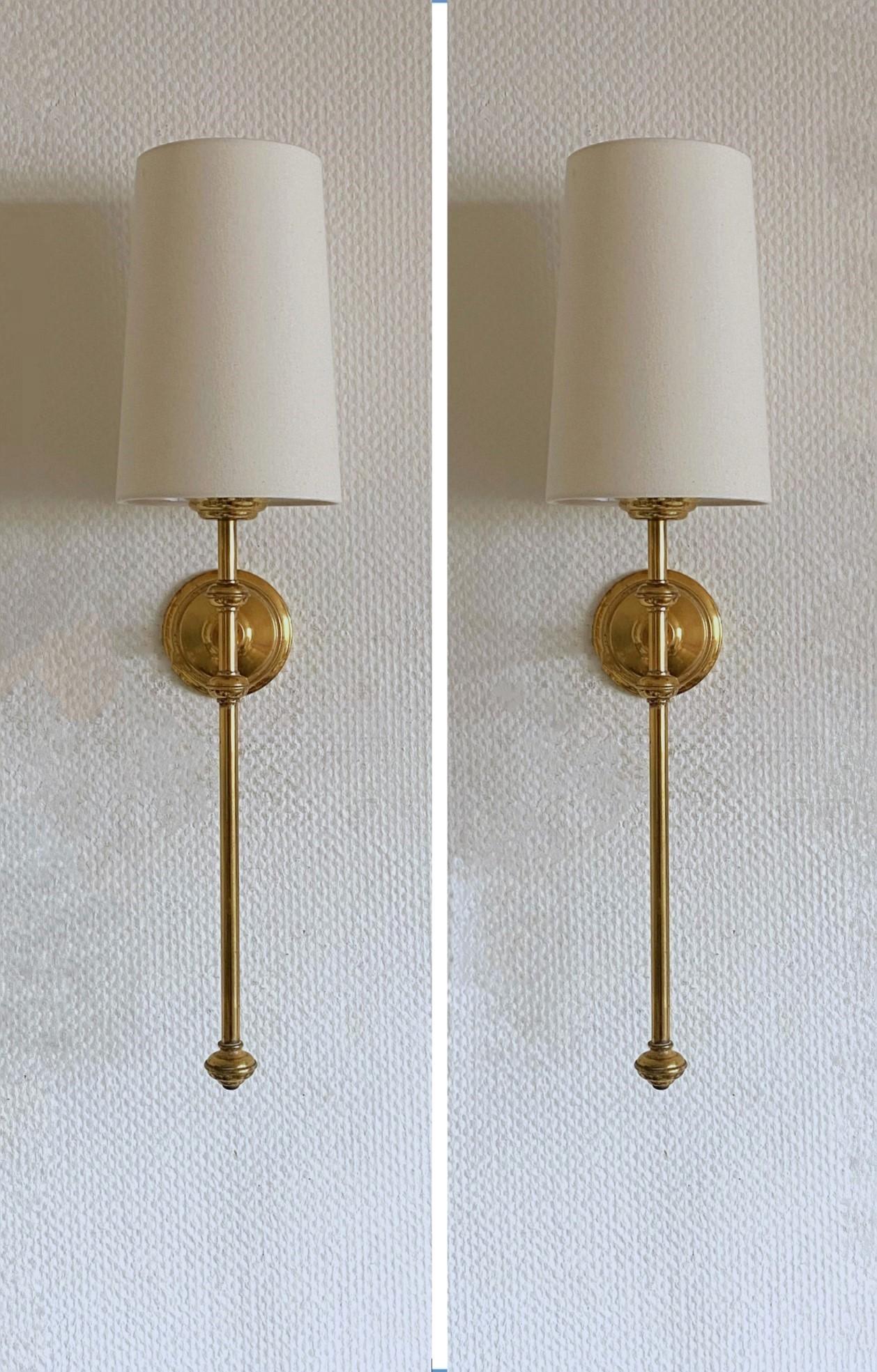Pair of tall Art Deco torchiere wall sconces in the style of Maison Jansen, France, 1955-1959. Very elegant design made of brass with conical off-white linen shades. Each sconce takes one Edison E14 candelabra screw bulb up to 60watt.
In very good