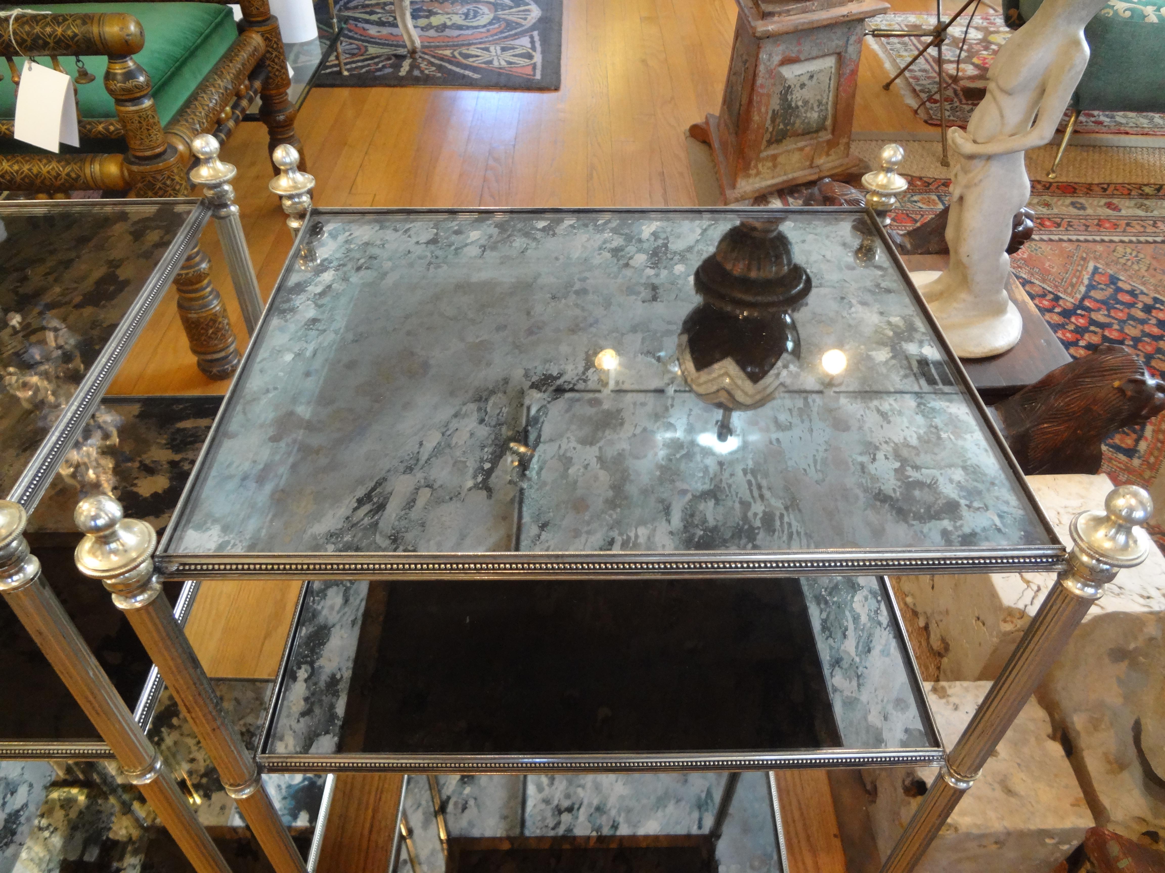 Stunning pair of vintage French Maison Jansen or Maison Baguès style silver plated three-tiered tables, side tables, end tables, drink tables or cigarette tables. This hard to find pair of French neoclassical style or Louis XVI style silver tables
