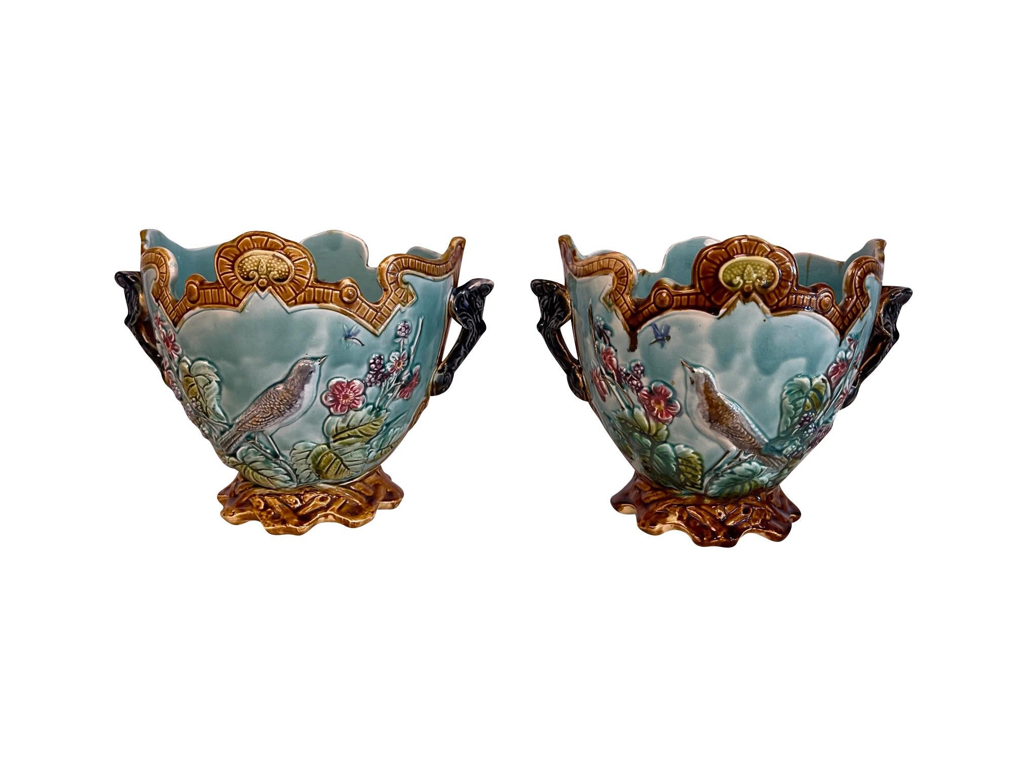 Decorate a table or a console with these colorful, antique Majolica planters. Created in France circa 1880, the sculptural ceramic cachepot stands on tree branch-shaped feet; the pot is decorated with hand-painted flowers and birds with green leaf