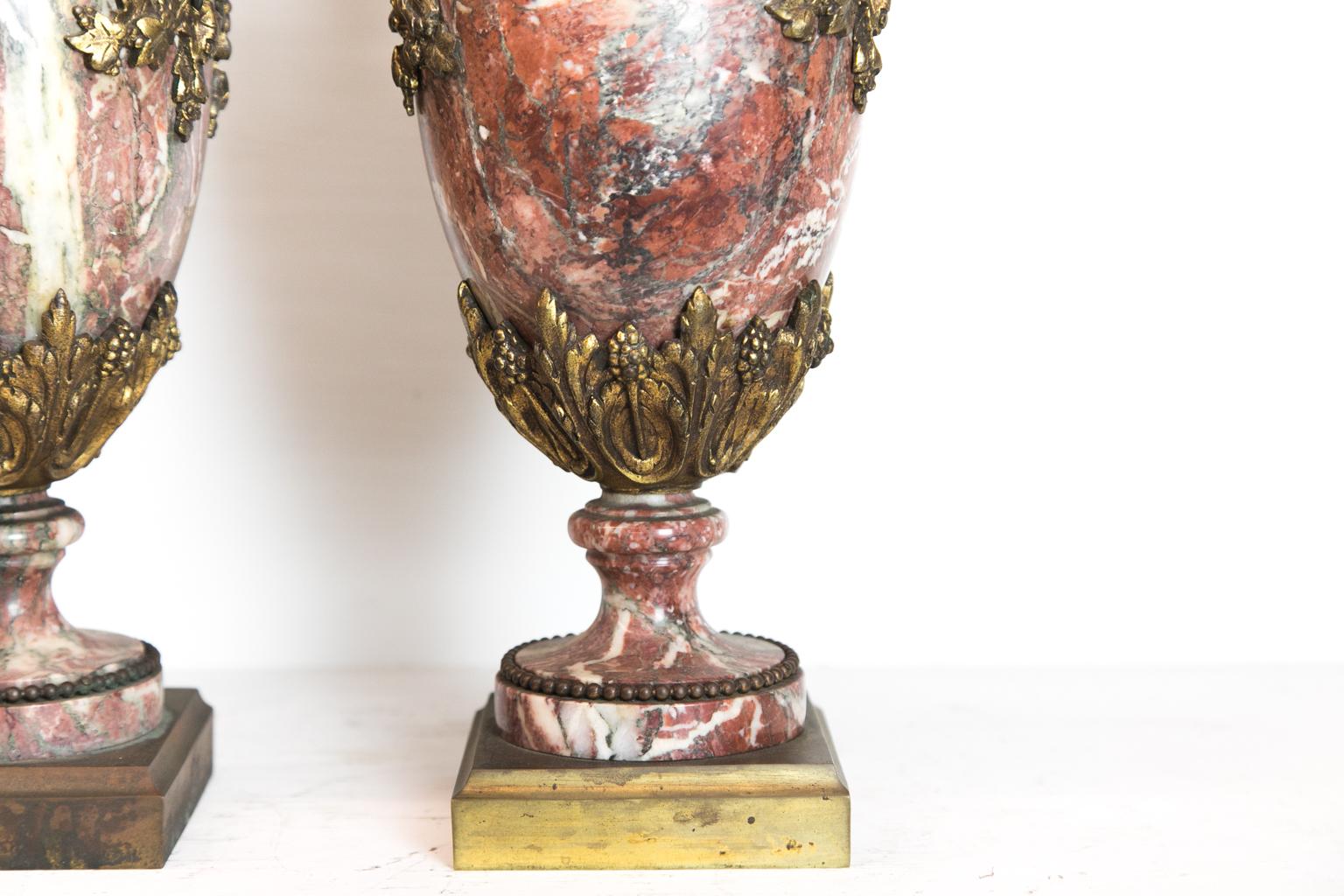 Pair of French marble and ormolu cassolettes, the removable lids have a pineapple finial, the top of the bases with a reticulated frieze, with twig and grapevine handles, and there is acanthus leaf and grape design on the base. The marble is a rojo