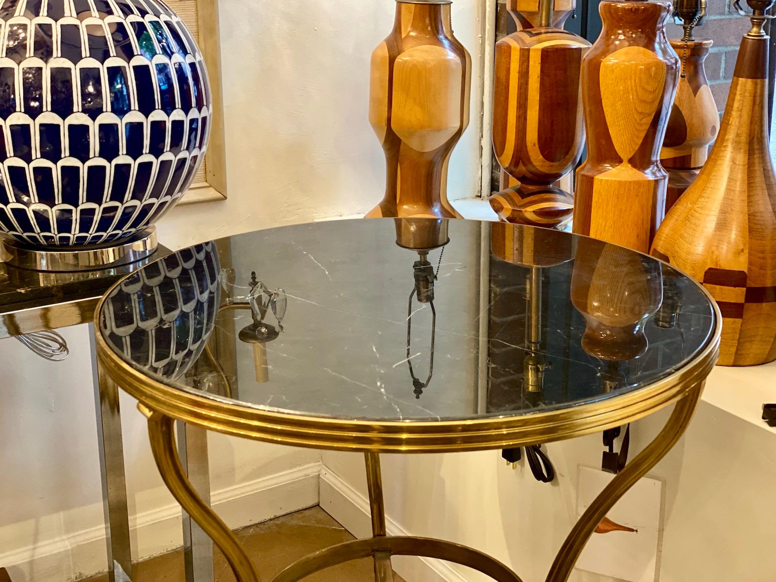 A pair of circa 1950's French polished bronze neoclassic side tables with polished black marble.

Measurements:
Height: 30