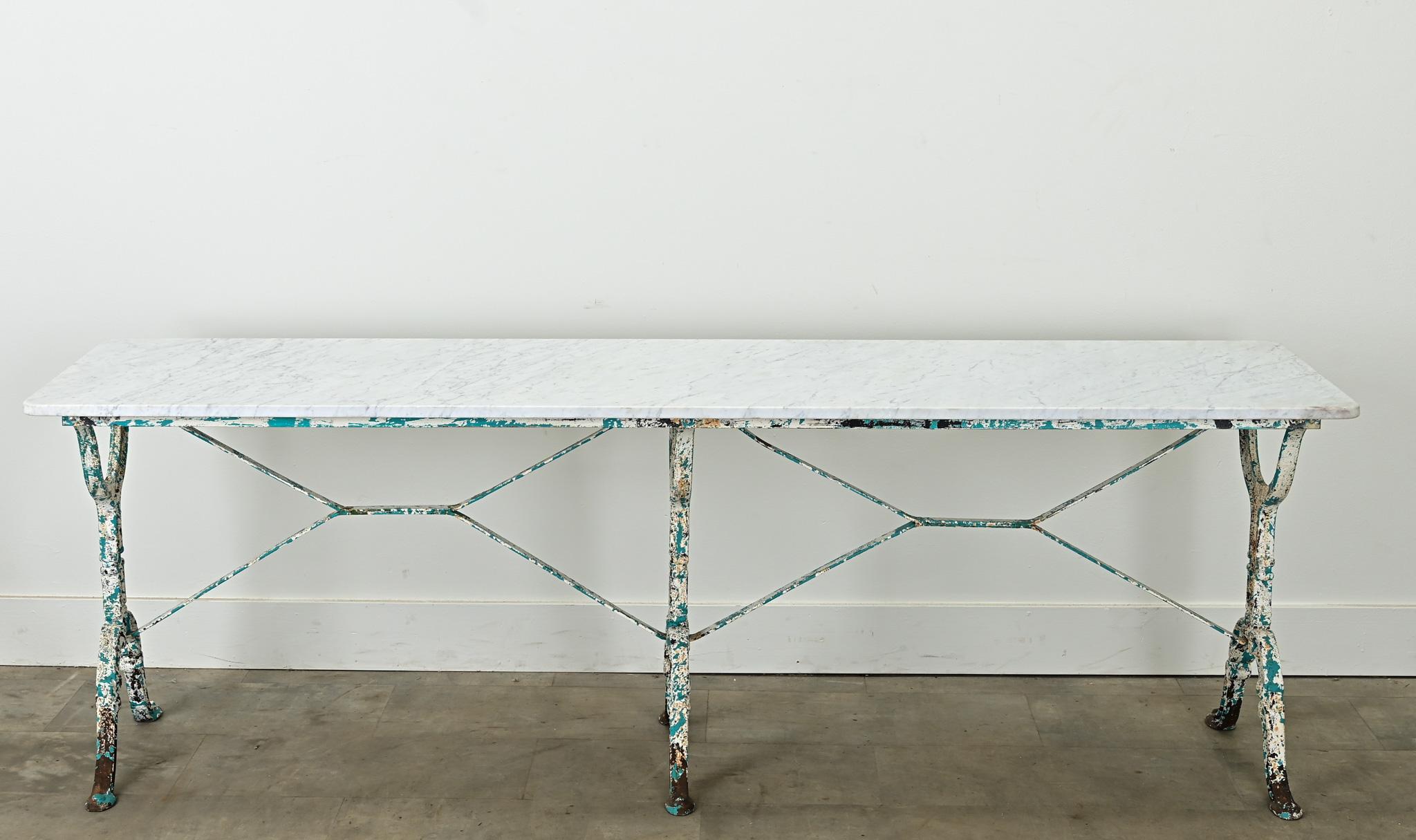 A pair of long bistro tables from France. The more recent white marble tops make for a durable surface and sit over iron bases with a worn paint finish. Perfect for interior or outdoor dining, a sofa table or a console. Be sure to view the detailed