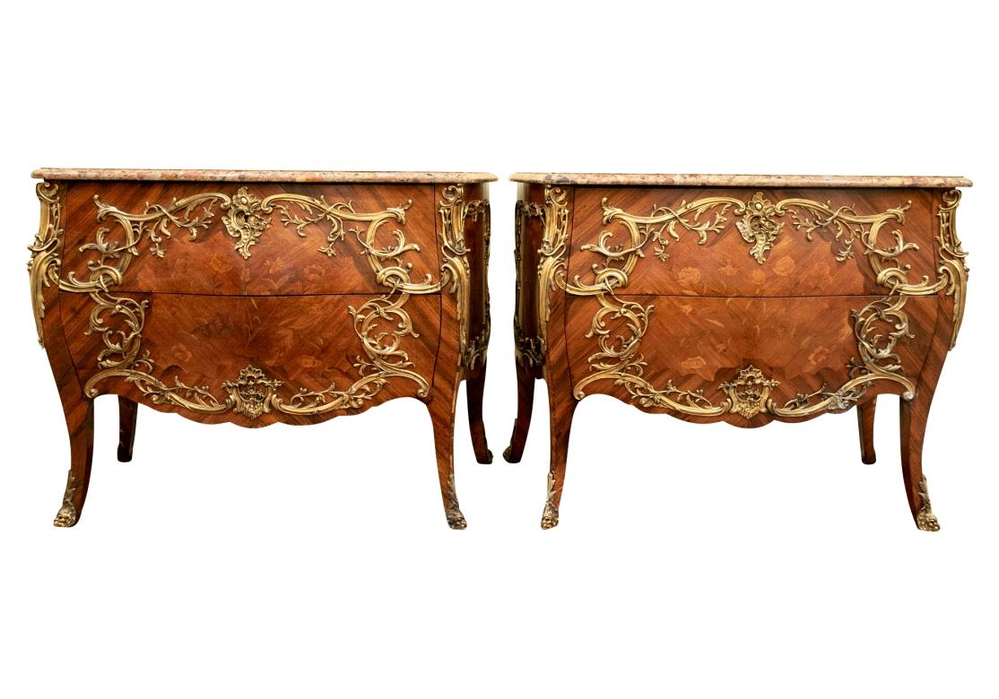 Pair of French commodes with conforming specimen marble tops and two drawers with large cartouche form bronze mounts with trailing leaves and vines and handles that are part of the vines. The front with intricate shell form escutcheon plates and