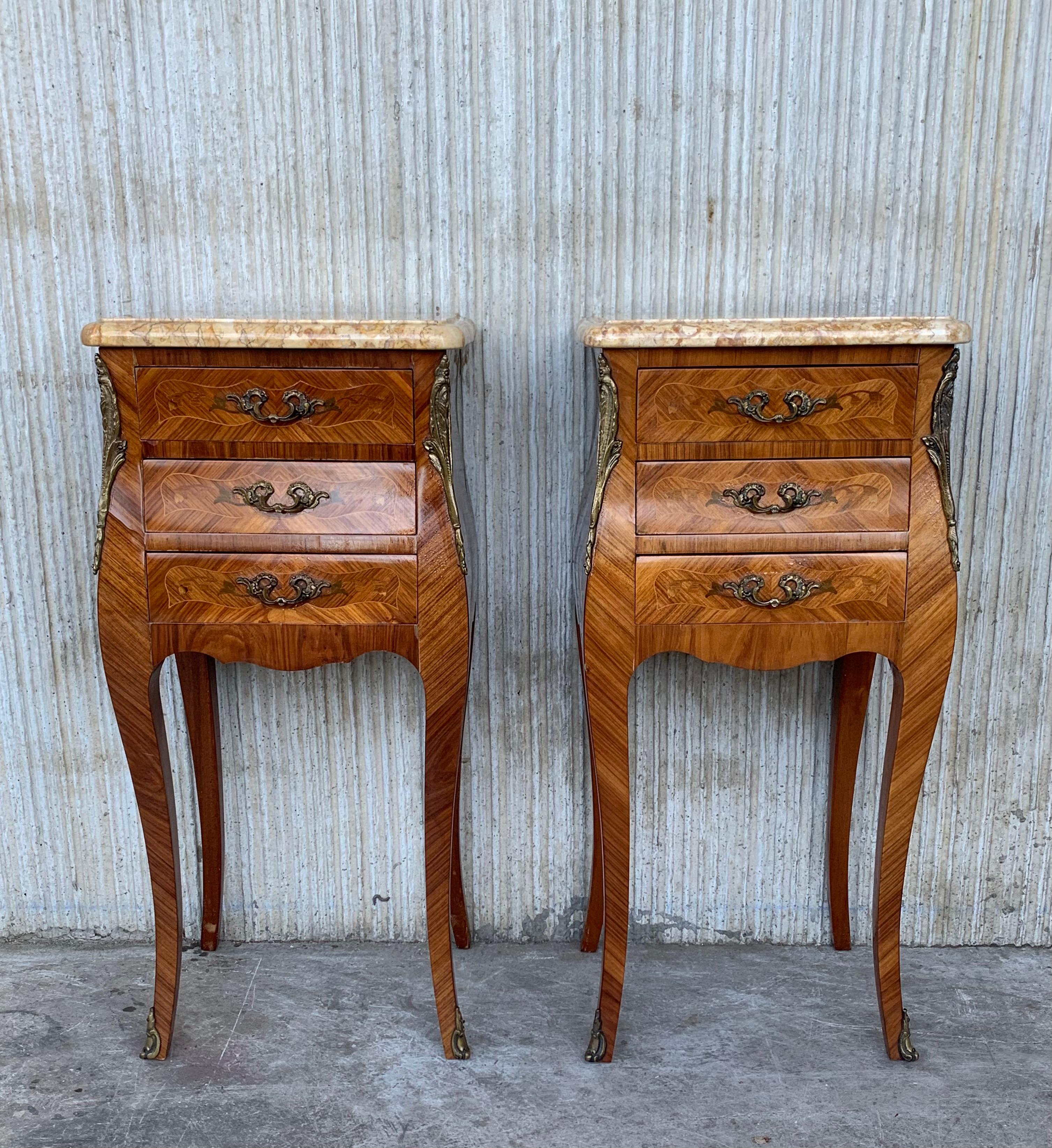 Matched Louis XV style kingwood nightstands, each with three drawers featuring floral Marquetry on a bookmatched kingwood ground. The pieces have a floral Marquetry in both sides and retain their original and beautiful marble tops and are