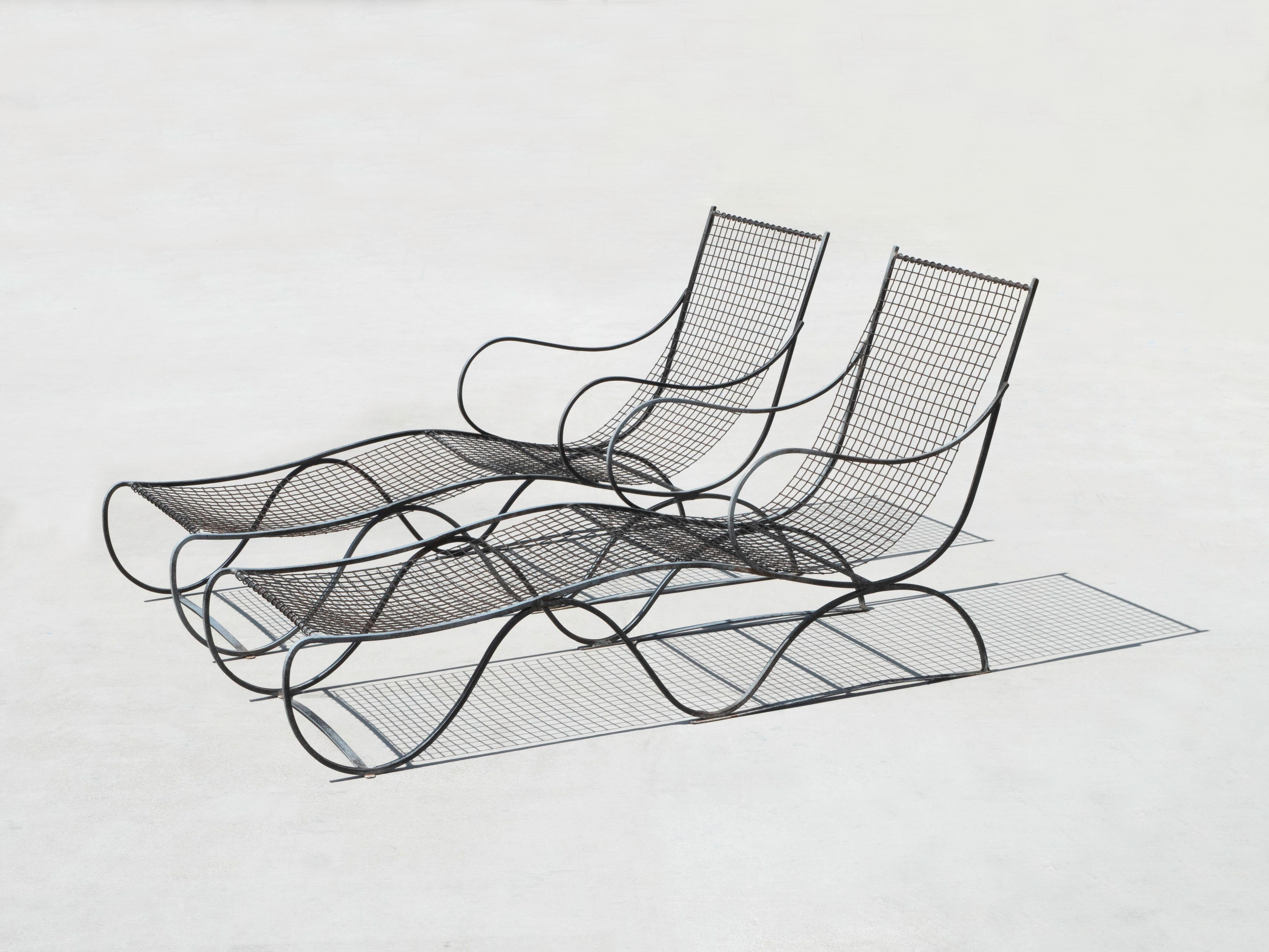 Pair of French iron lounge chaises from the 1930’s/1940’s. The playful juxtaposition between the delicate curved lines and the solid wrought iron make them a highly unique design that will last the ages. The chaises are comprised of solid wrought