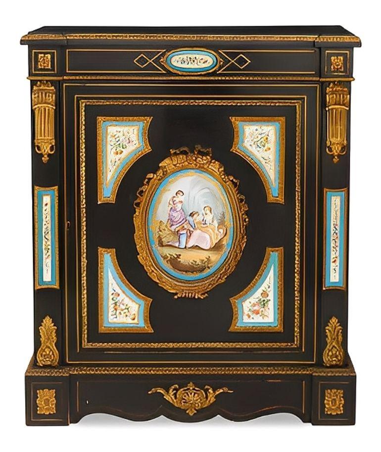 A striking matched pair of ebonized meubles d’appui (parlor/side cabinets), each richly mounted with gilt‑bronze (ormolu) and hand‑painted Sèvres porcelain plaques. The rectangular tops with projecting/canted front corners sit above a frieze
