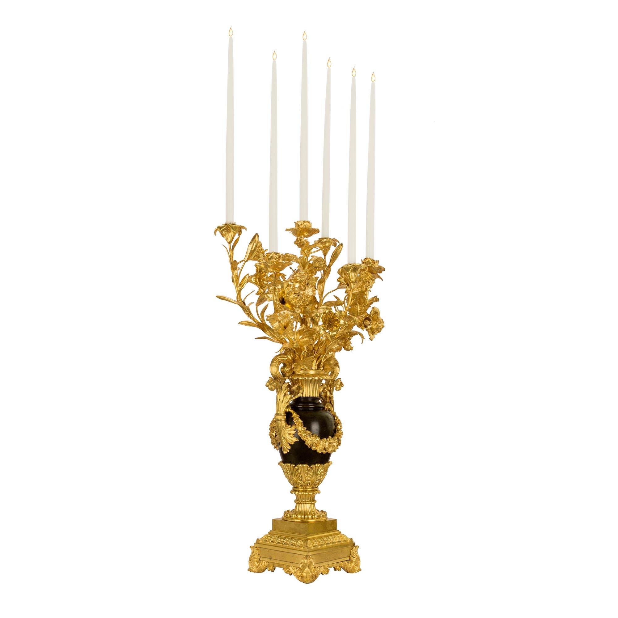 A spectacular and monumental scaled pair of French mid 19th century Louis Philippe six arm candelabras in ormolu and patinated vertigris bronze. The pair are raised by an impressive square base above four scrolled acanthus leaf supports. The reeded