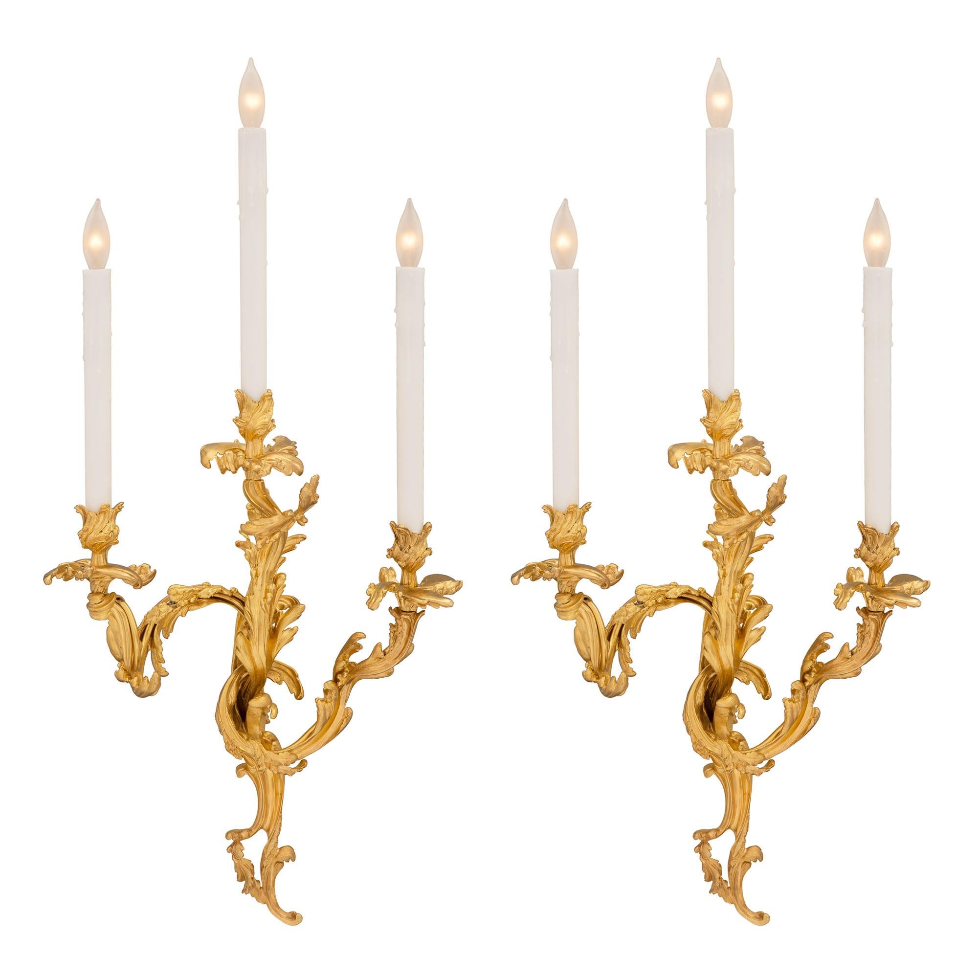 A stunning pair of French mid 19th century Louis XV st. ormolu sconces. Each three armed sconce is centered by a fine pierced scrolled foliate back plate with lovely richly chased leaves. Each of the beautifully scrolled arms display lovely and most
