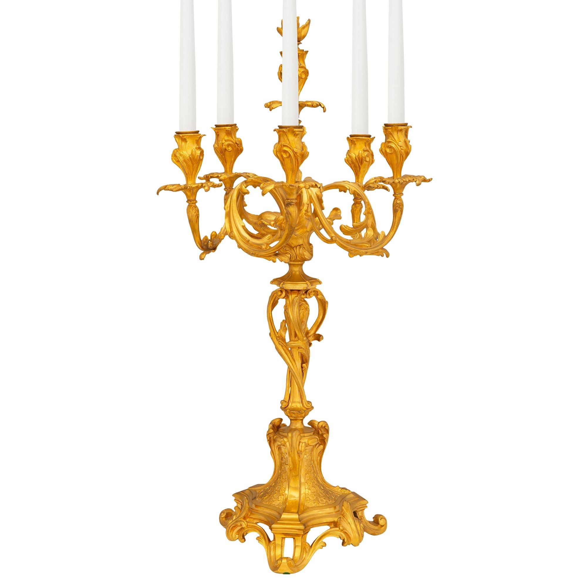 A striking and high quality pair of French 19th century Louis XV st. ormolu candelabras. Each six arm candelabra is raised by a beautiful pierced base with a scalloped triangular shape, fine scrolled foliate feet, beautiful central leaf and