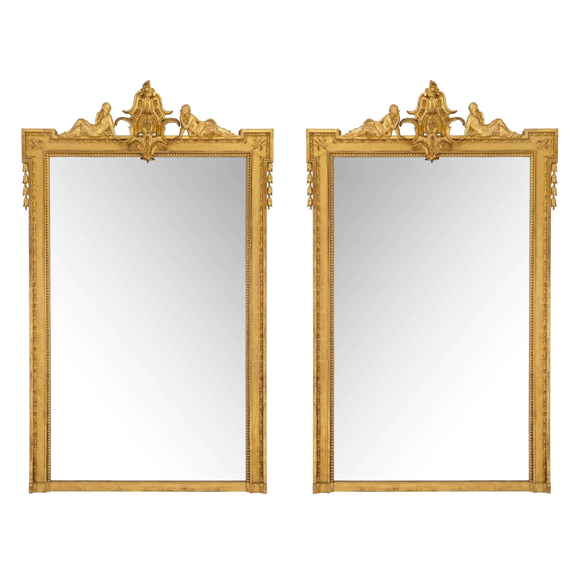 Paire impressionnante et de grande taille de miroirs en bois doré de style Louis XVI du milieu du XIXe siècle. La paire comporte un grand rang de perles à côté d'une bordure moulée avec un motif d'œuf et de fléchette. Au sommet se trouve une réserve