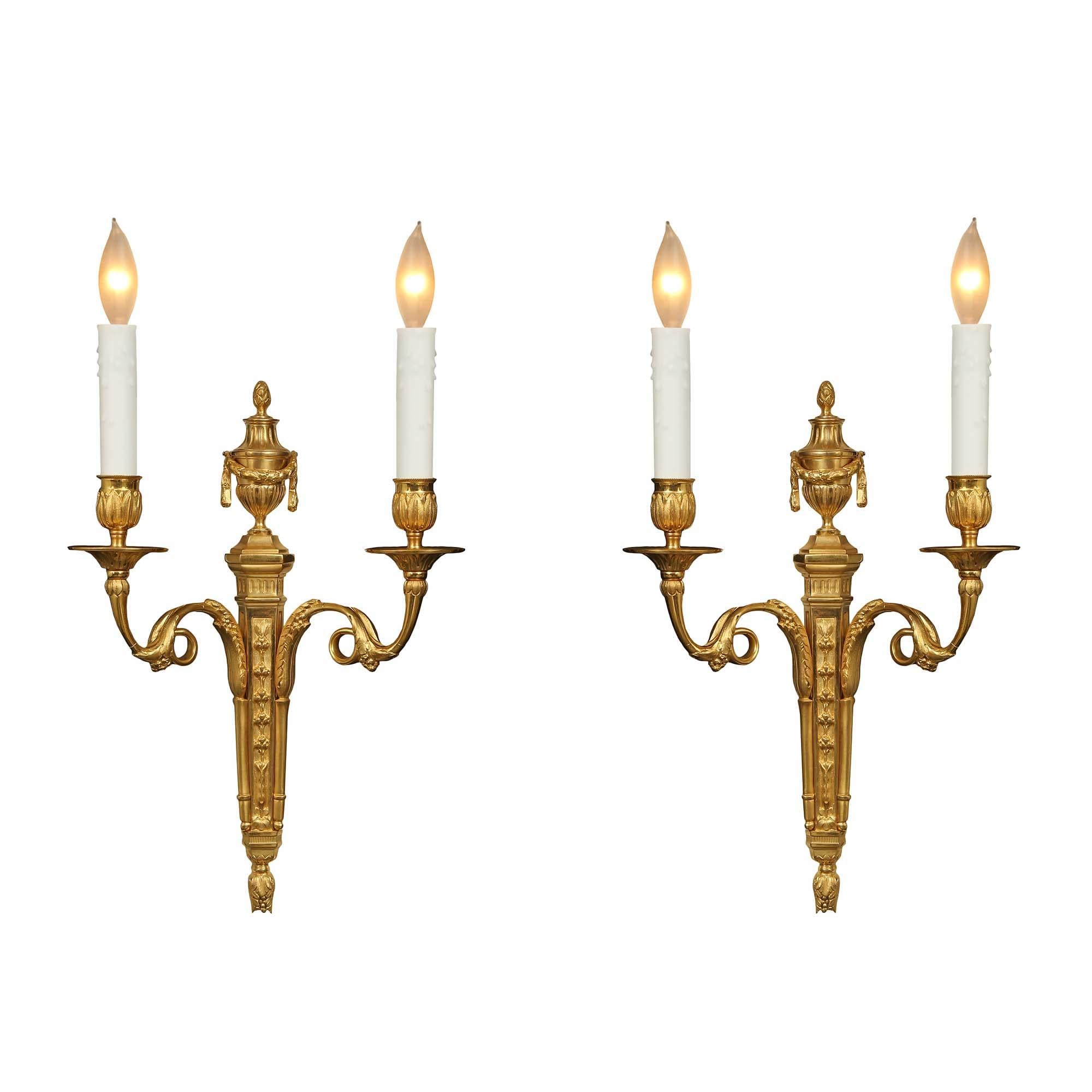 An elegant and high quality pair of French mid 19th century two arm Louis XVI st. ormolu sconces. The pair with a tapered backplate designed with fruits has two 'S' scrolled arms with a loop. The richly chased arms end with acanthus leaf decorated