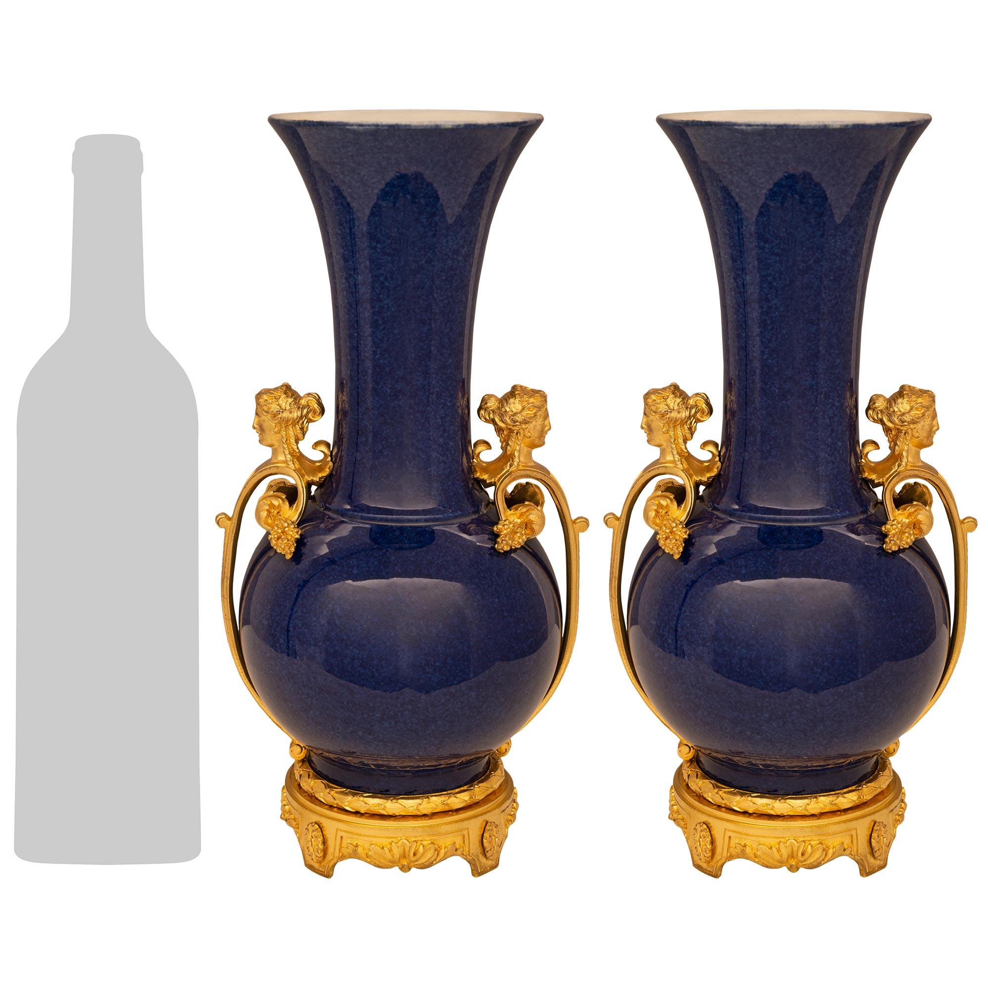 An exquisite and high quality pair of French mid 19th century Louis XVI st. blue cobalt Porcelain and Ormolu vases. Each vase is raised by a scrolled Ormolu base with acanthus leaves and rosettes, and an Ormolu berried laurel band above. The